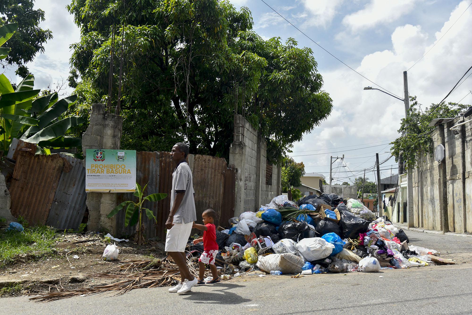Un hombre pasea junto a su hijo frente a una gran cantidad de basura (Foto: Neal Cruz - Diario Libre)