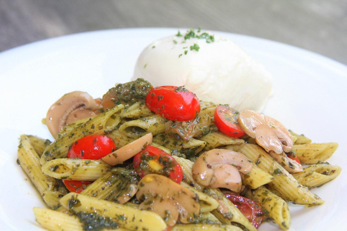 Penne en pesto de albahaca, hongos salteados, burrata, parmesano y tomates cherry.