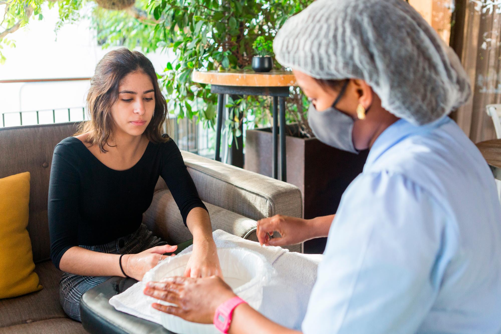 Eva Lucía Aquino Espinal recibe su manicura con todos los protocolos de seguridad.