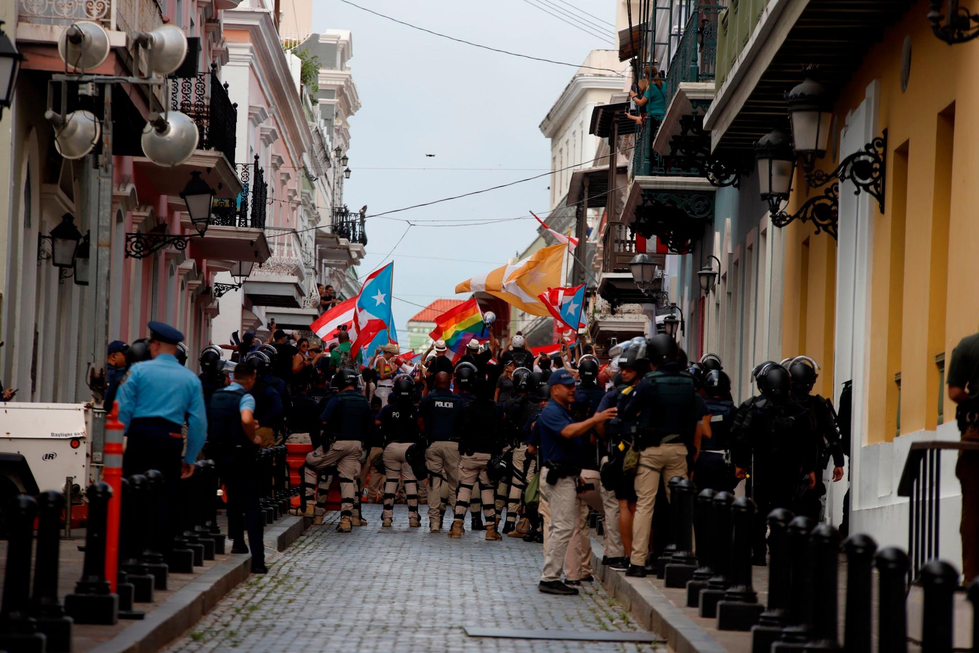 Agentes custodian la celebración de los vecinos de San Juan (Puerto Rico) de la renuncia efectiva del exgobernador Ricardo Rosselló.