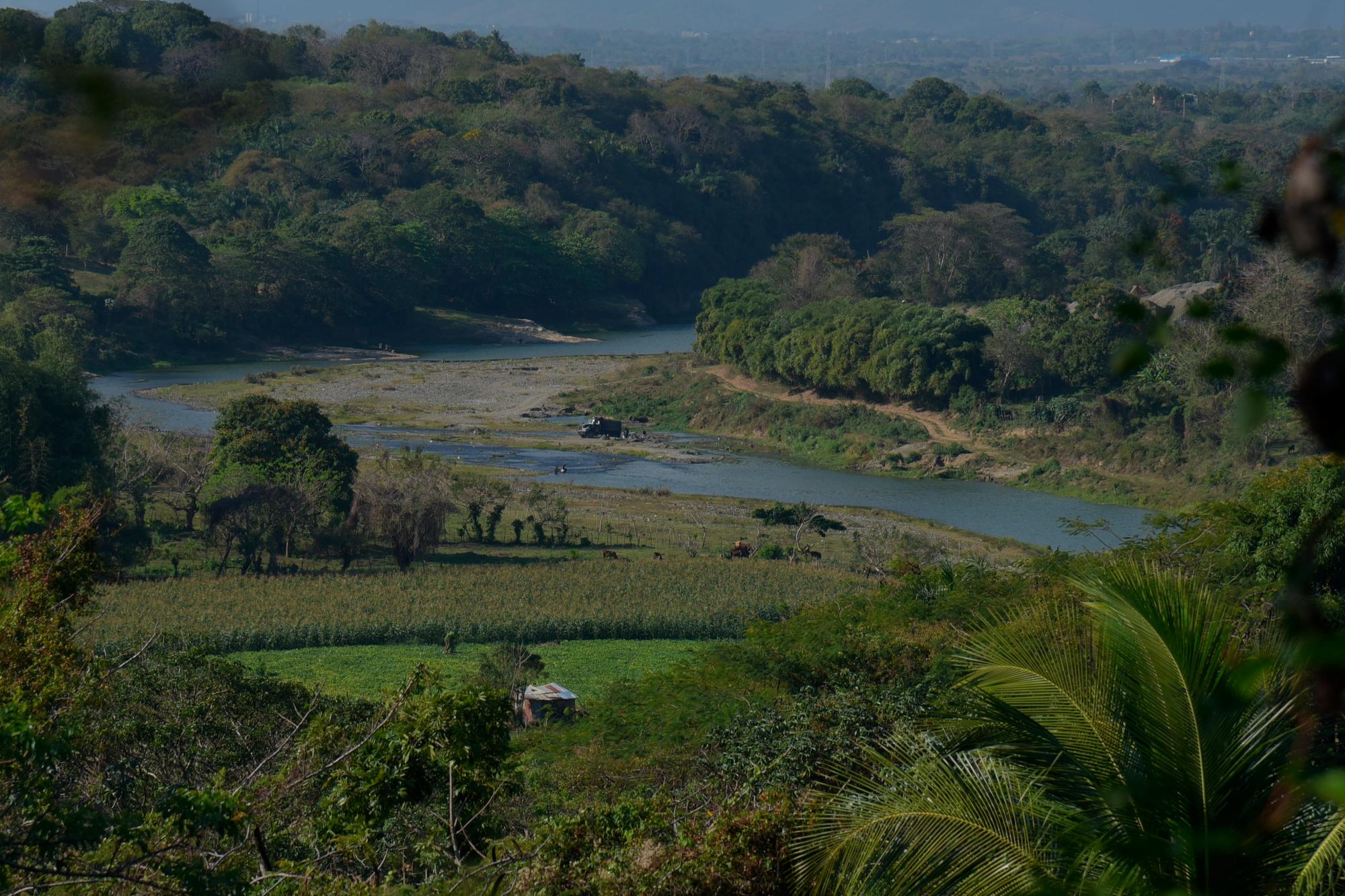 Un camión se avista desde lejos mientras se abastece de arena en el río Haina.