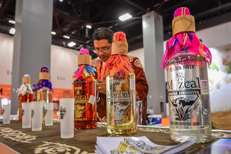 Una persona dispone las botellas de mezcal de Tamaulipas (México) durante la inauguración de la feria Fibega.