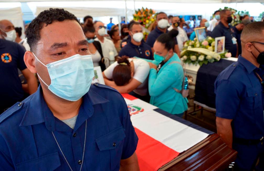 Un bombero llora mientras sostiene el ataúd de unos de sus compañeros.