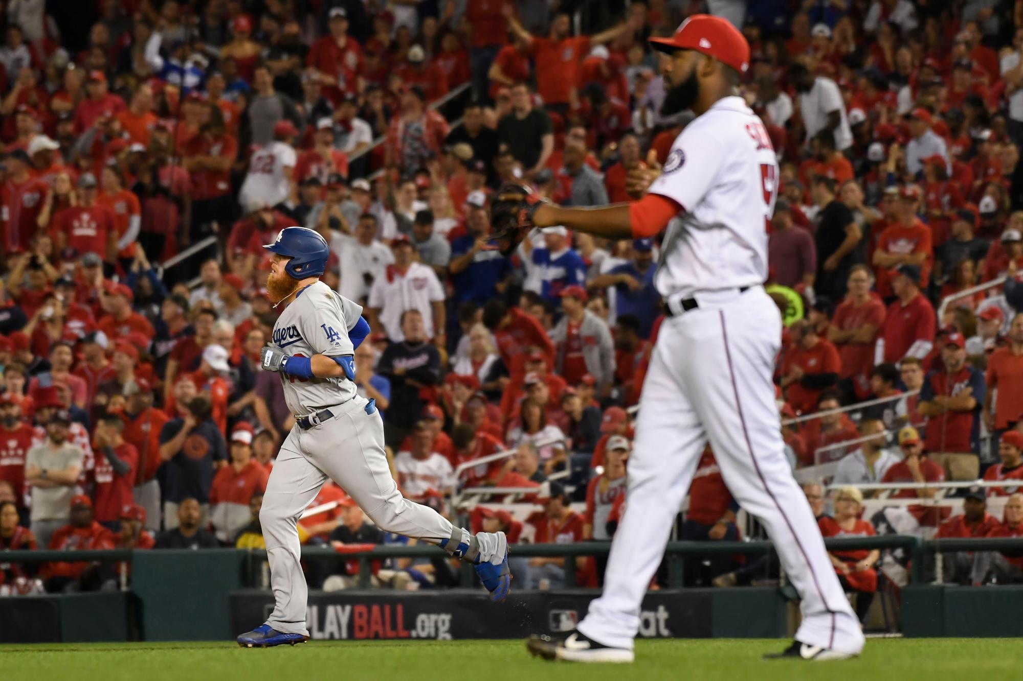 Justin Turner, de los Dodgers de Los Ángeles, a la izquierda, recorre las bases después de pegar un jonrón de tres carreras contra el lanzador relevista de los Nacionales de Washington Wander Suero, a la derecha, durante la sexta entrada en el Juego 3 de la Serie de División de la Liga Nacional el domingo 6 de octubre de 2019, en Washington.