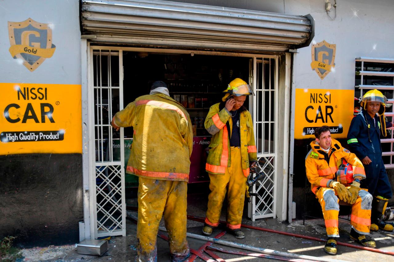 Bomberos descansan tras sofocar fuego en ferretería. 