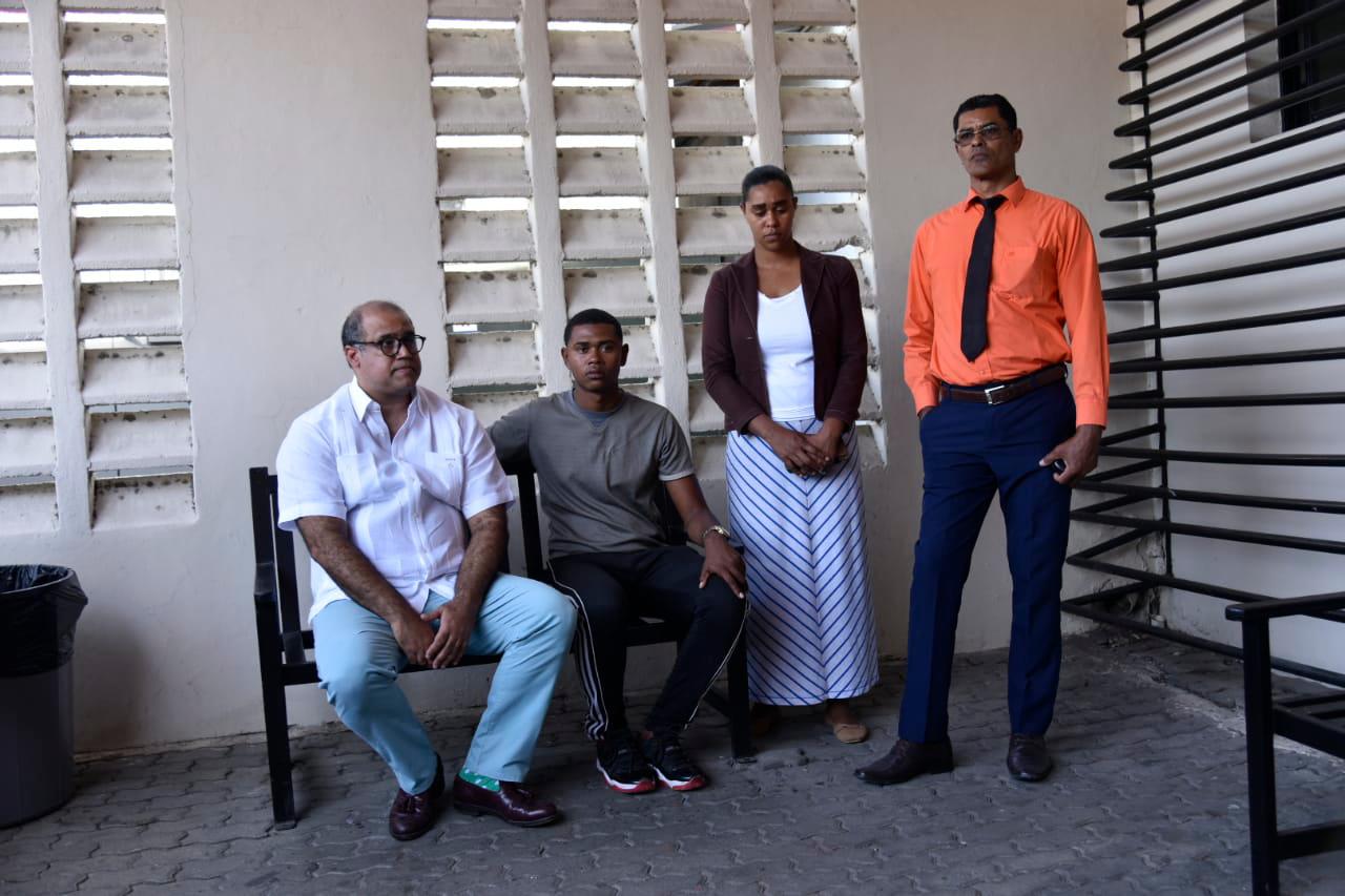 El abogado Miguel Valerio sentado junto al cabo José De Jesús, de pie su hermana y su padre.