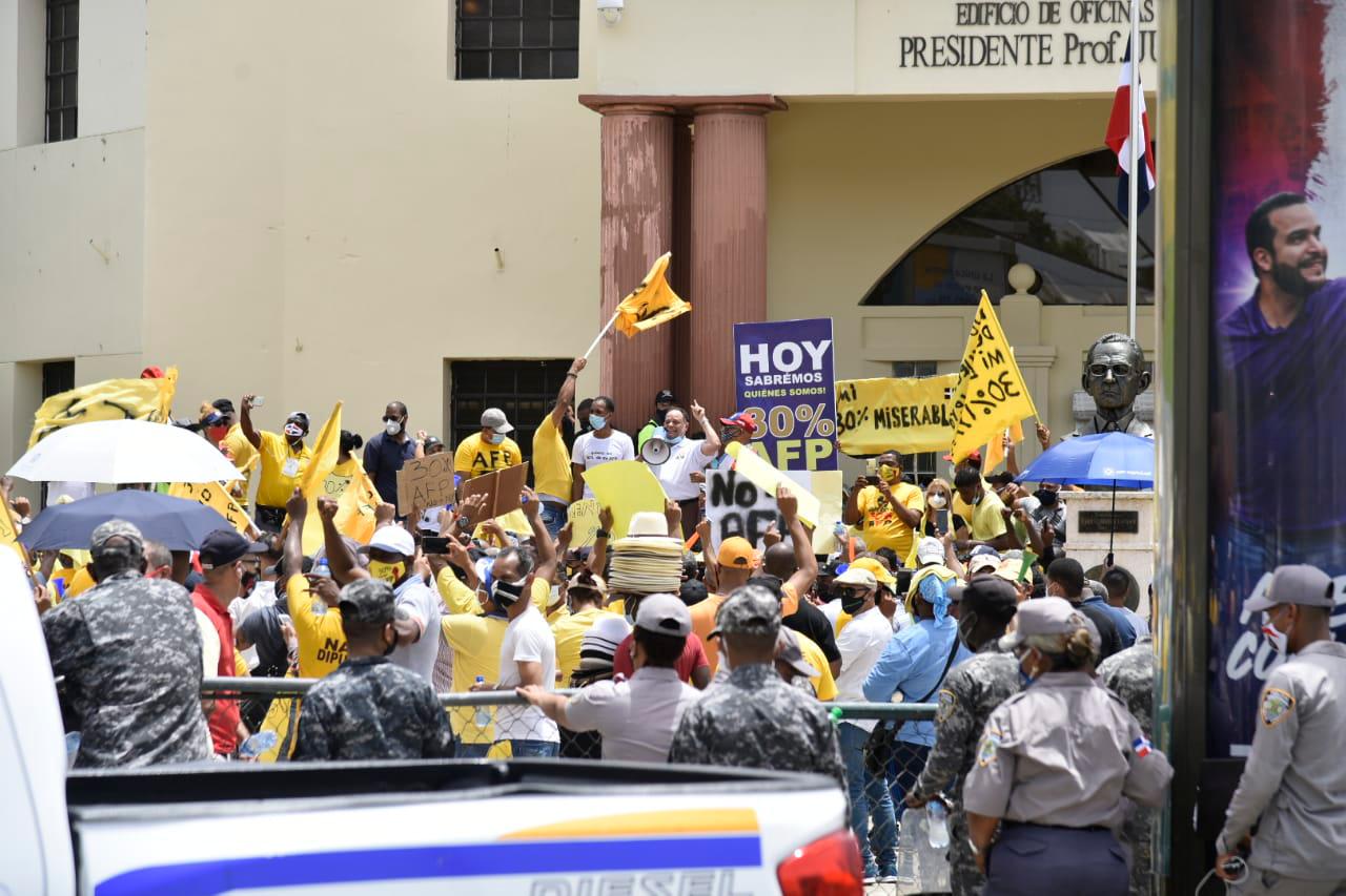 Cordón policial rodea a las personas que protestan exigiendo la devolución del 30 % de los fondos de pensiones.