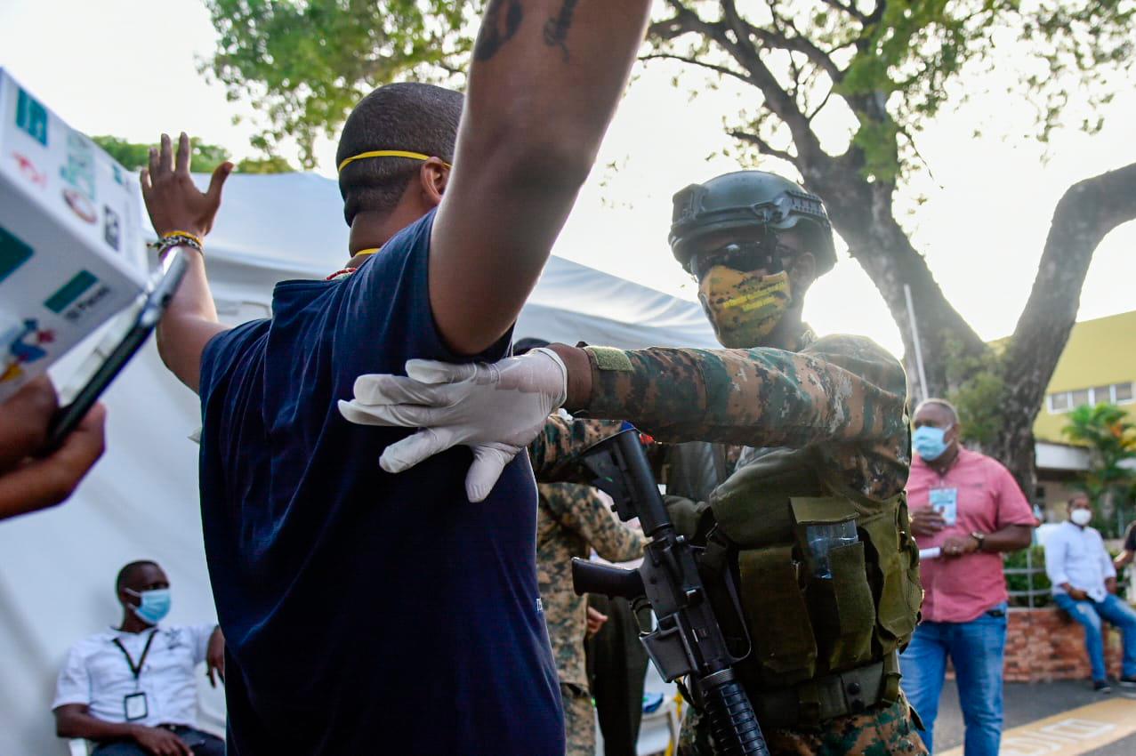Distrito Nacional, República Dominicana: Un guardia del  Ejército Nacional requisa a un ciudadano en la entrada de la Junta Central del Distrito Nacional. Aún  continúa el conteo de los votos de  las pasadas elecciones del 5 de julio de 2020. 
