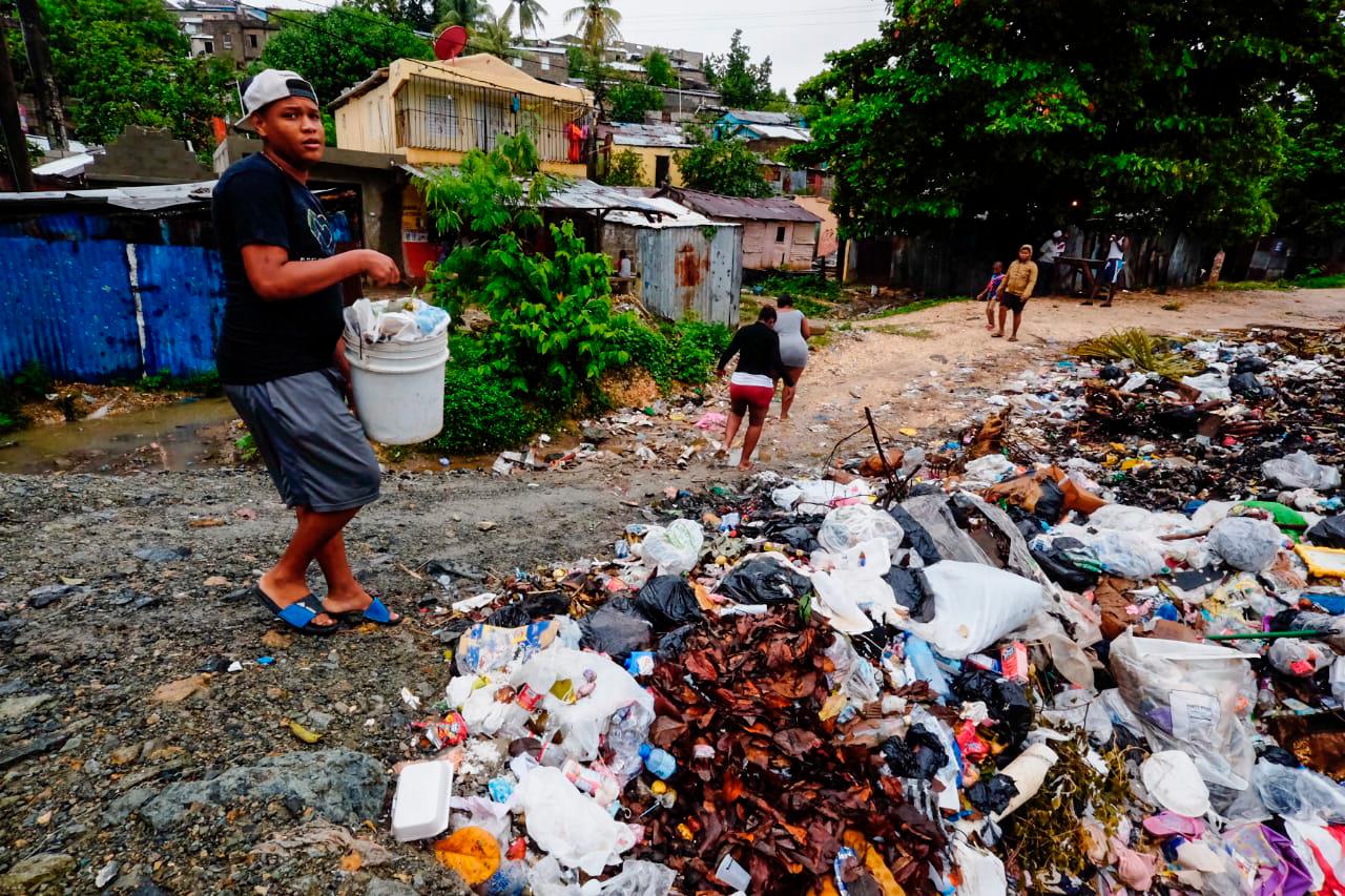 Un hombre tirando basura en un lugar que ya está cubierto de desechos, cerca del río.