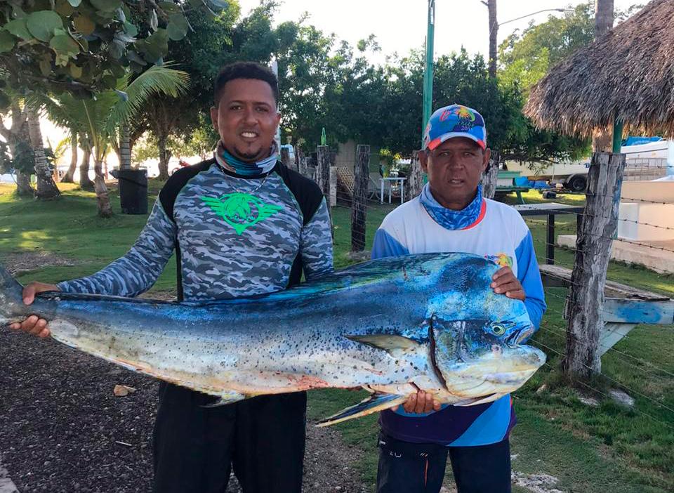 Álido Báez, izquierda, sostiene con otro pescador un dorado capturado frente a Bayahíbe.