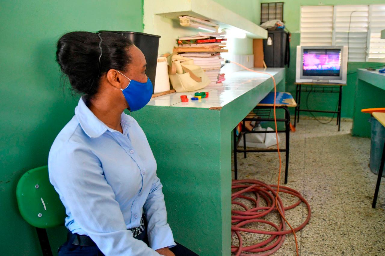 La profesora Sagrario Rodríguez observa en un viejo televisor las transmisiones del Minerd.