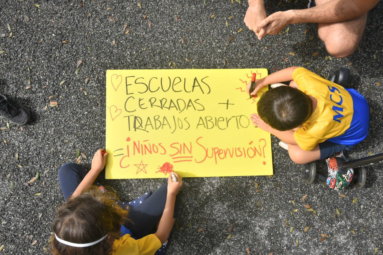 Unos niños colorean un cartel usado por el Colectivo PpepRD para cuestionar que los menores de edad no tienen supervisión en sus casas.