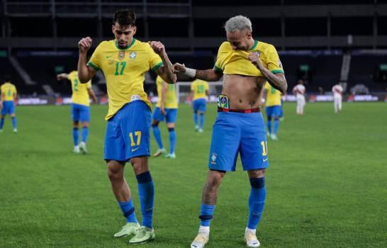 Lucas Paquetá (17), de la selección de Brasil, festeja con su compañero Neymar después de anotar el primer gol ante Perú en la semifinal de la Copa América, el lunes 5 de julio de 2021 (AP/Silvia Izquierdo)