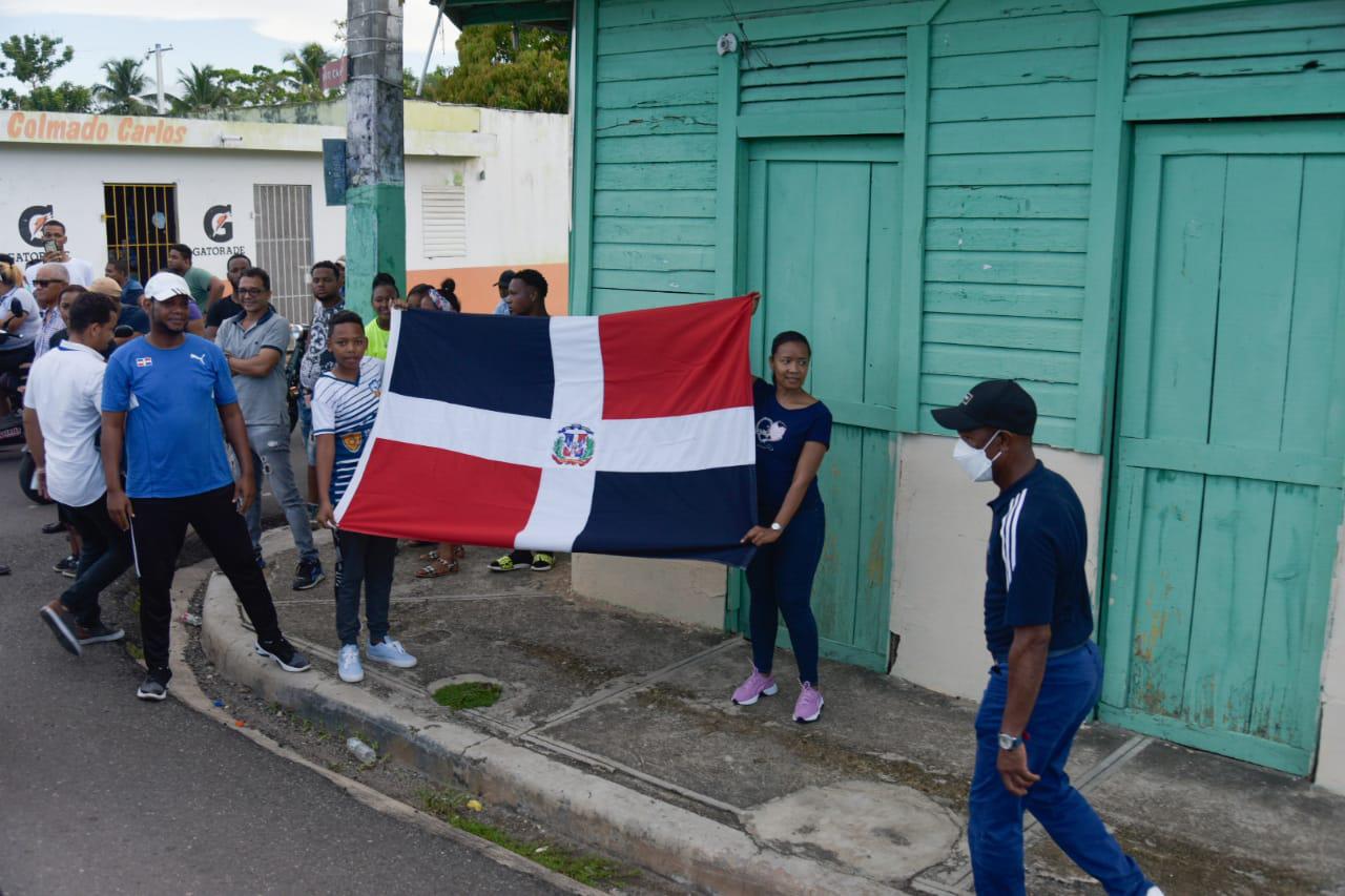 Lugareños de Bayaguana muestran una bandera dominicana en una de las calles por donde pasó la caravana del pesista Zacarías Bonnat, que conquistó una medalla de plata en los Juegos Olímpicos, Tokio-2020. (DL/Dania Acevedo)