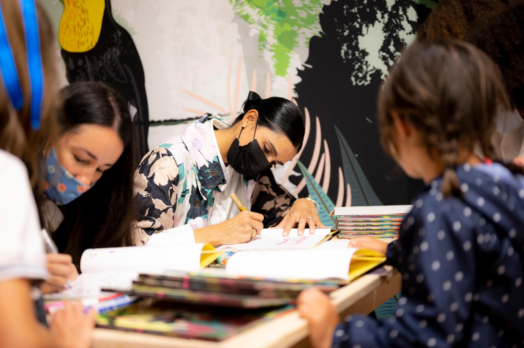 Taína Almodóvar y Atenas Hernández firman los libros de las personas que participaron en la actividad.