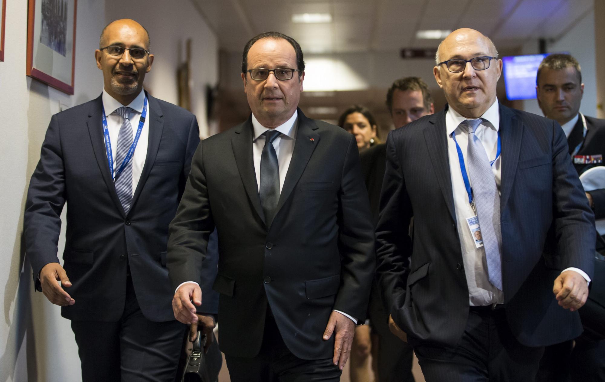 El presidente francés, François Hollande (c), acompañado de su ministro de Finanzas, Michel Sapin (dcha), y del secretario de Estado para Asuntos Europeos, Harlem Desir, a su llegada a una rueda prensa tras finalizar la cumbre de líderes de la eurozona.