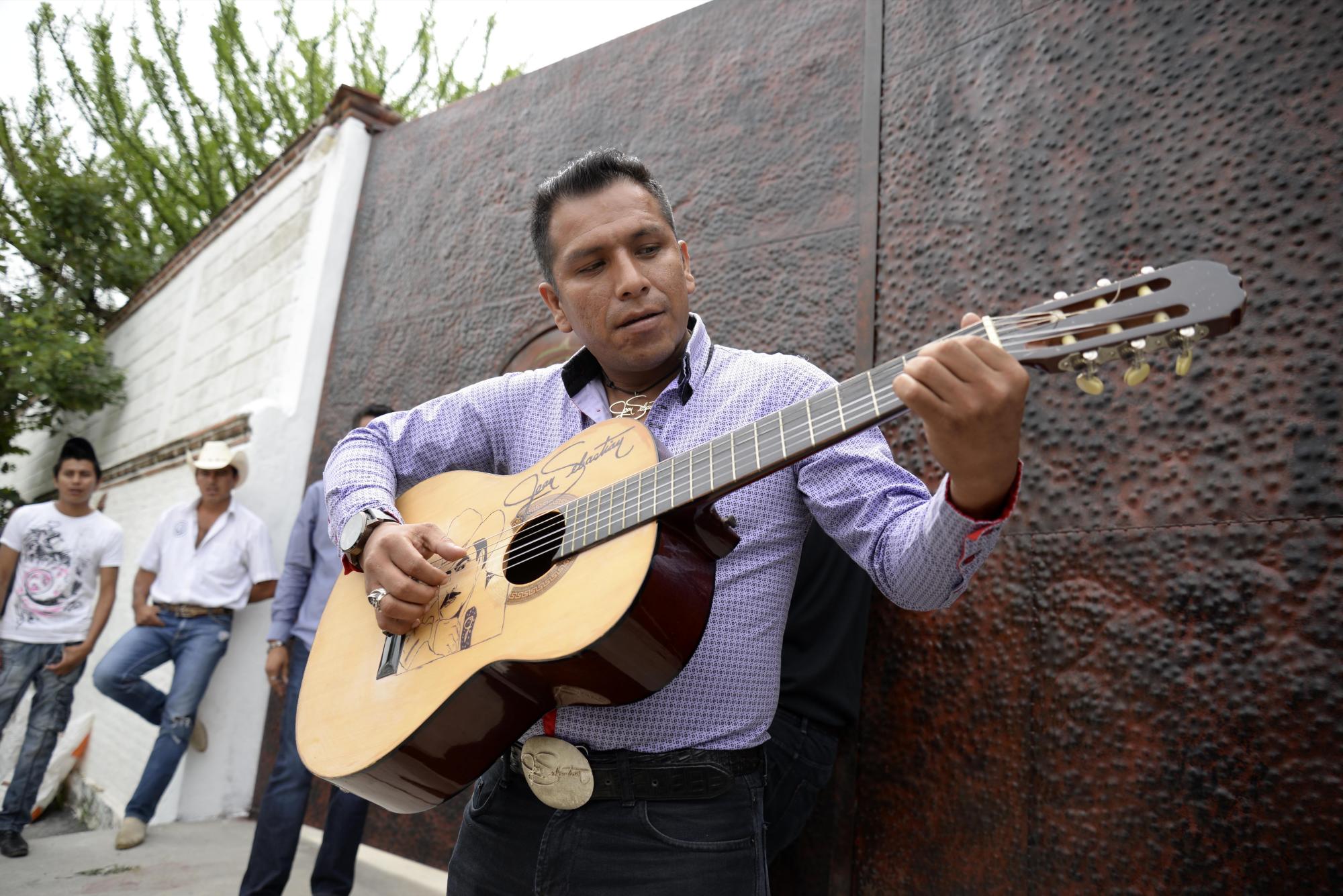 Domingo David, un admirador de Joan Sebastian, toca la guitarra afuera de la casa del cantante mexicano en Teacalco, México, el martes 14 de julio del 2015. Joan Sebastian murió el lunes tras una larga lucha con el cáncer. Tenía 64 años.