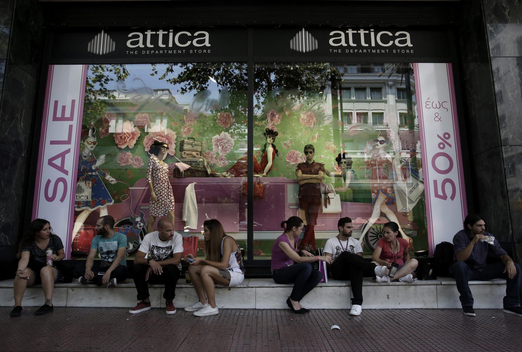 Varios jóvenes conversan a las puertas de una tienda en rebajas en el centro de Atenas, el 13 de julio de 2015. 