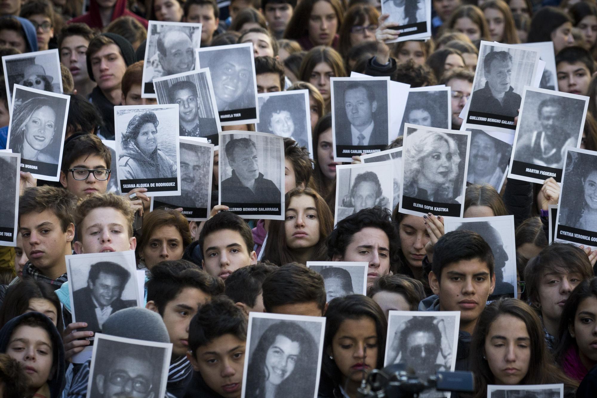 En esta imagen del viernes 17 de julio de 2015, gente con retratos de las víctimas del atentado en el centro comunitario judío AMIA, en el 21er aniversario del atentado terorista en Buenos Aires, Argentina. En el ataque murieron 85 personas en 1994, y sigue sin resolverse. 