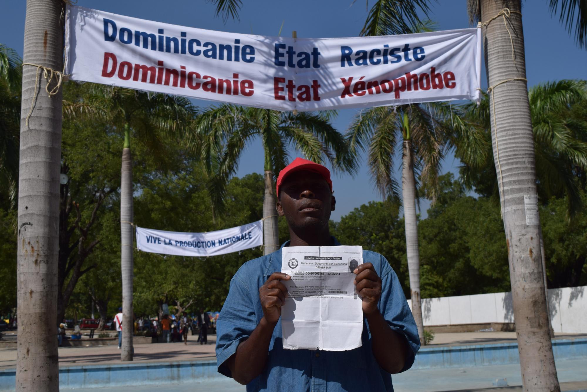 Un manifestante posa con un documento de inscripción del Plan de Regularización de Extranjeros de República Dominicana.