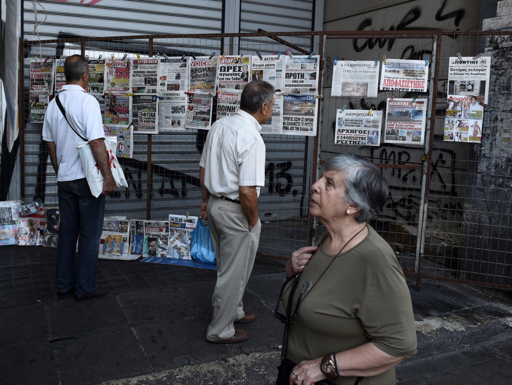Unas personas observan los titulares de la prensa en un kiosco en la plaza Omonia de Atenas, Grecia, el 23 de julio de 2015. 