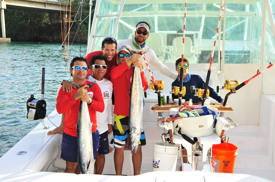 Daniel Medina Junior y Tony Costa  levantan las piezas capturadas en la embarcación donde la capturaron 