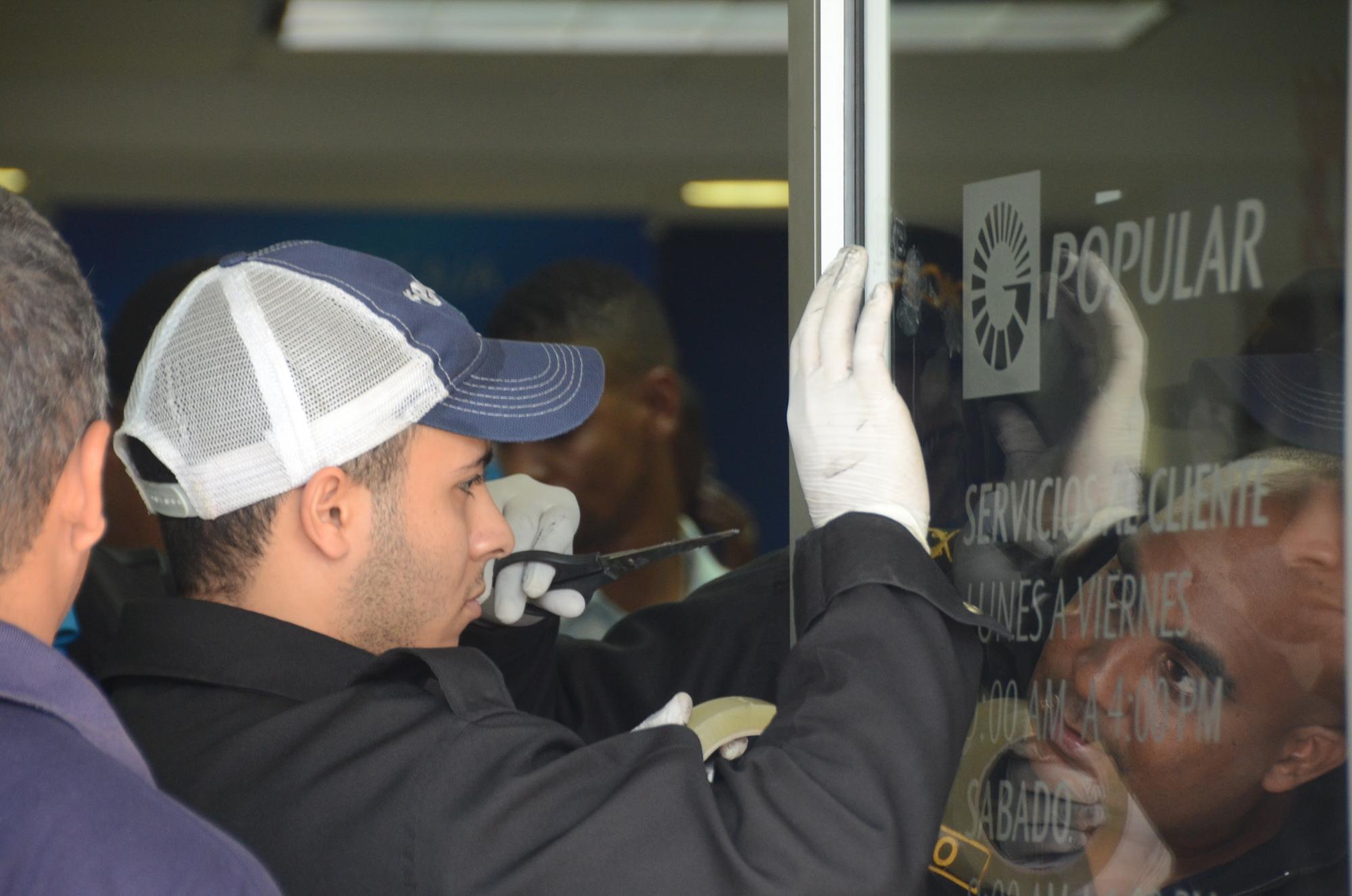 Investigadores de la Policía investigan el robo en la sucursal del Banco Popular asaltada