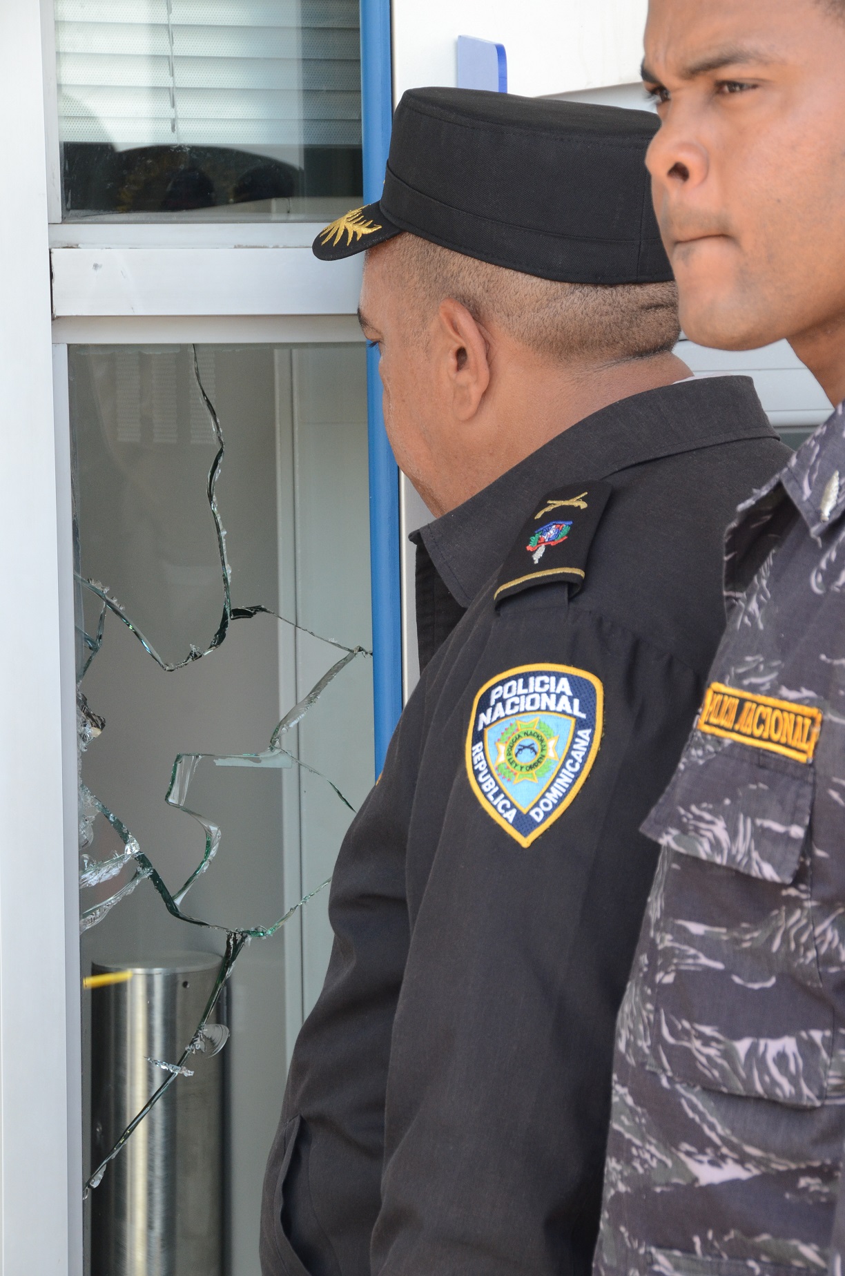Dos agentes policiales observan por un cristal roto de la sucursal del Banco Popular asaltada