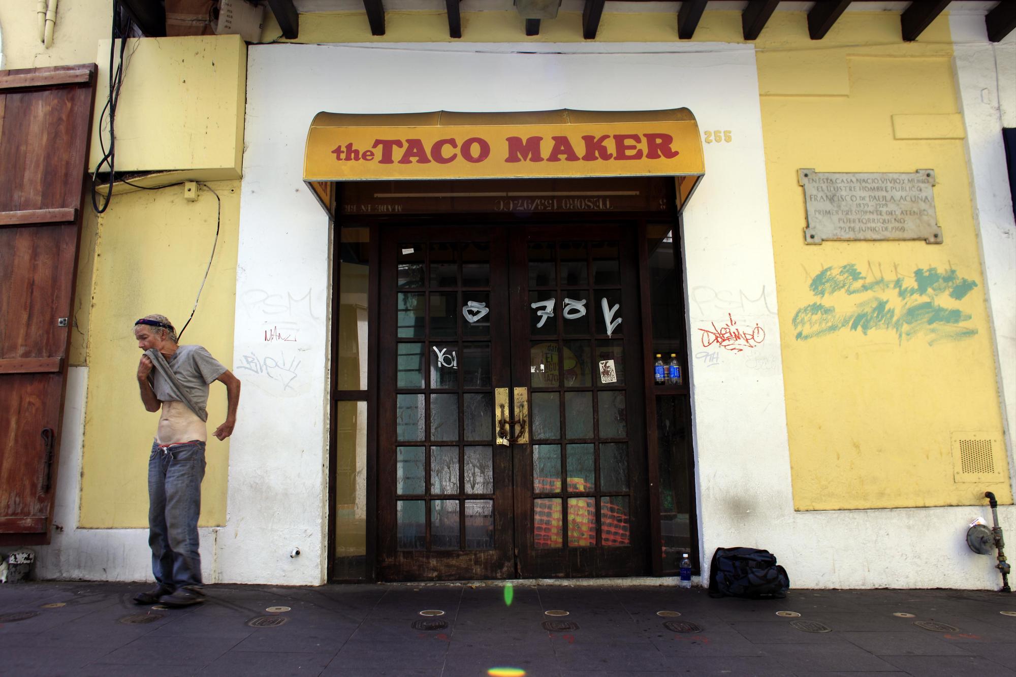 Un hombre sin hogar ante un restaurante de comida rápida cerrado en el distrito colonial de Viejo San Juan, Puerto Rico, el domingo 2 de agosto de 2015.