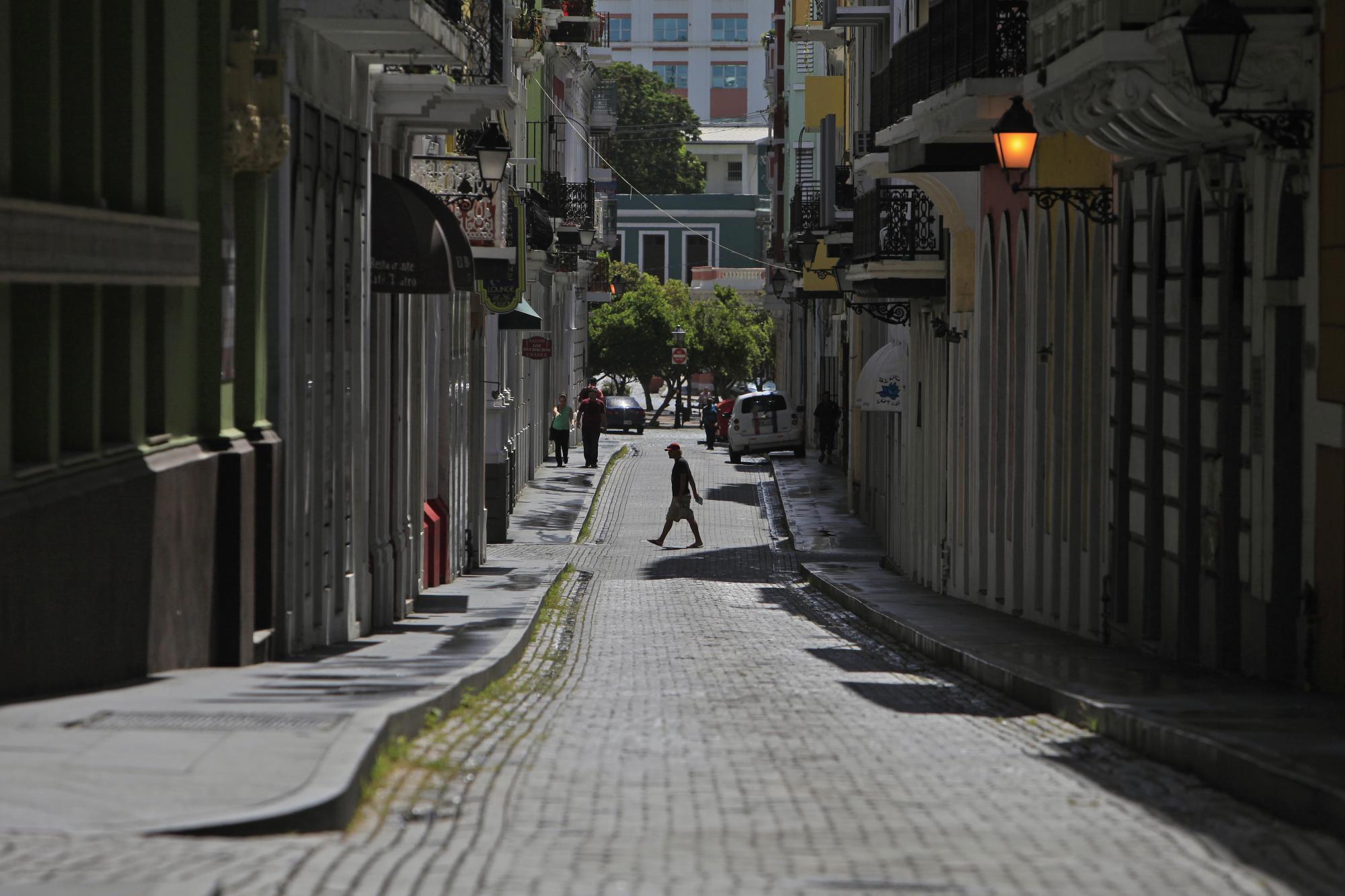 Un hombre cruza una calle de adoquines en el distrito colonial de Viejo San Juan, en Puerto Rico, el domingo 2 de agosto de 2015.