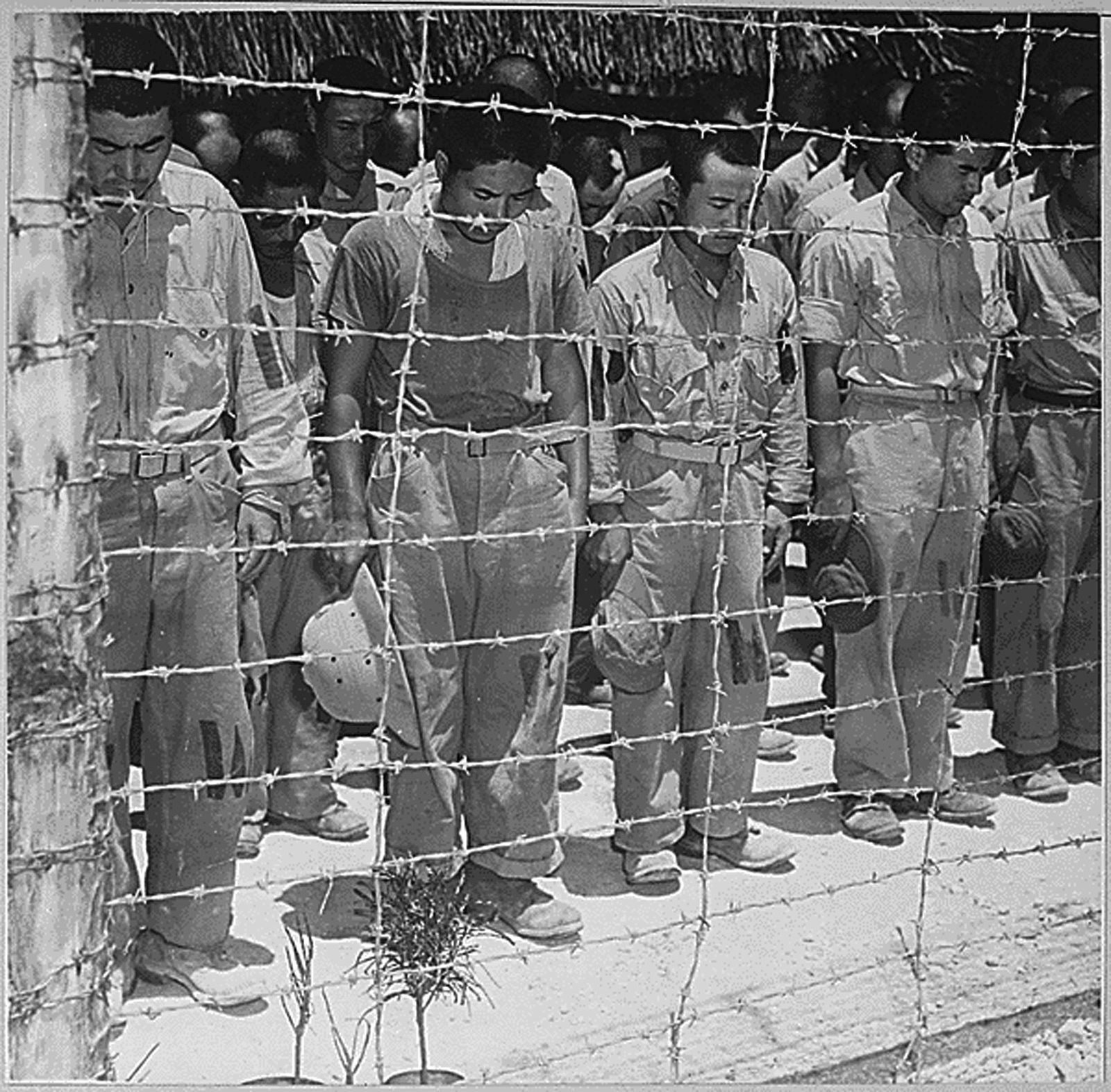 Fotografía de archivo facilitada por la Administración de Archivos Nacionales de Estados Unidos (NARA, en inglés) que muestra prisioneros de guerra japoneses que realizan una reverencia mientras escuchan al emperador Hiroito que anuncia la rendición nipona en el centro POW en GUAM el 15 de agosto de 1945. Japón recuerda este año el 70 aniversario de la tragedia en la que fallecieron miles de personas en cuestión de segundos. A finales de 1945, año en que cayó la bomba, un total de 140.000 personas habían muerto a causa de los efectos de la radiación.