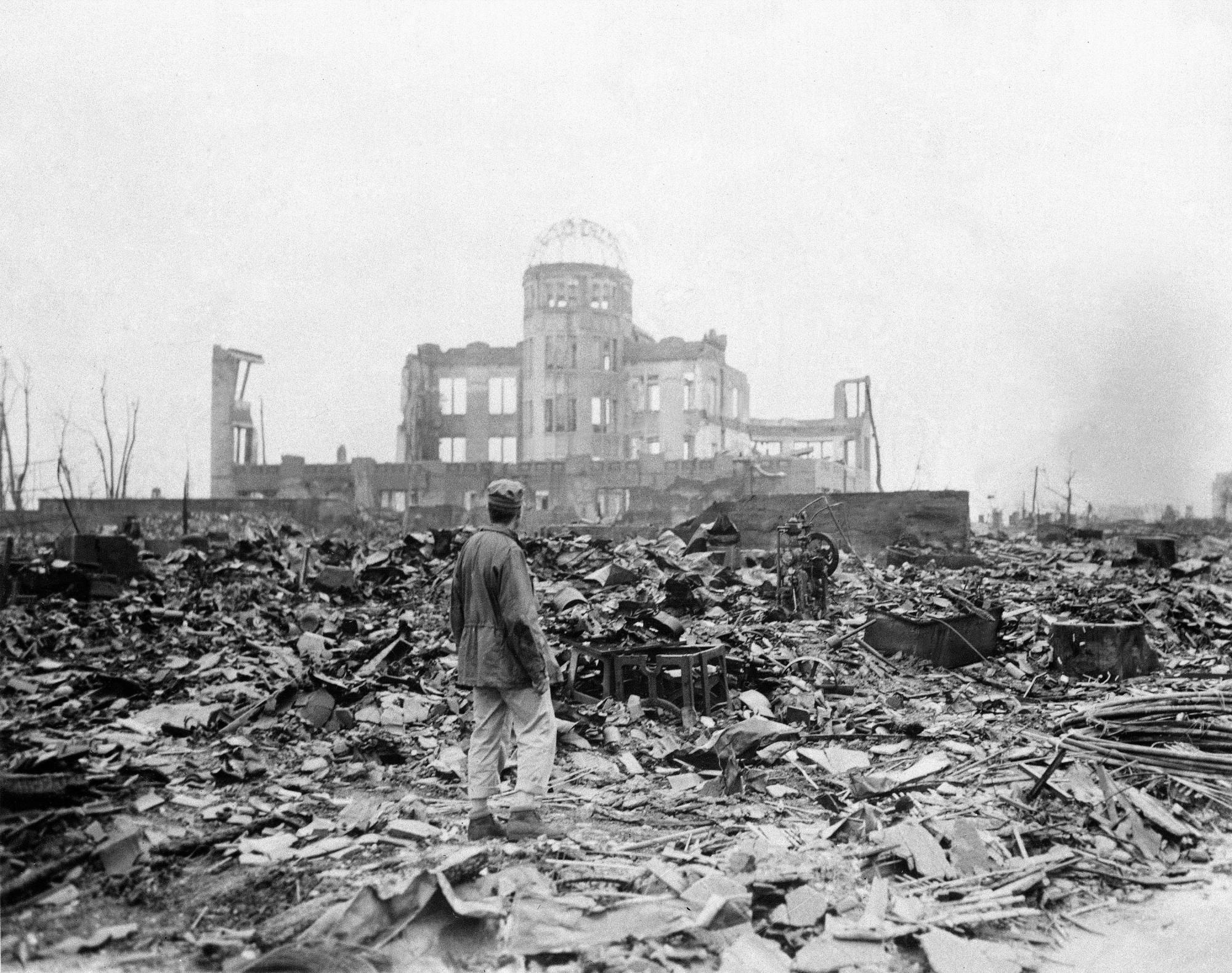 En esta imagen, tomada el 8 de septiembre de 1945, un reportero extranjero de pie sobre los escombros ante los restos de un edificio que en su día fue un centro de exposiciones y sede gubernamental en Hiroshima, Japón, un mes después del lanzamiento de la primera bomba atómica lanzada en una guerra, por fuerzas de Estados Unidos, el 6 de agosto de 1945. 