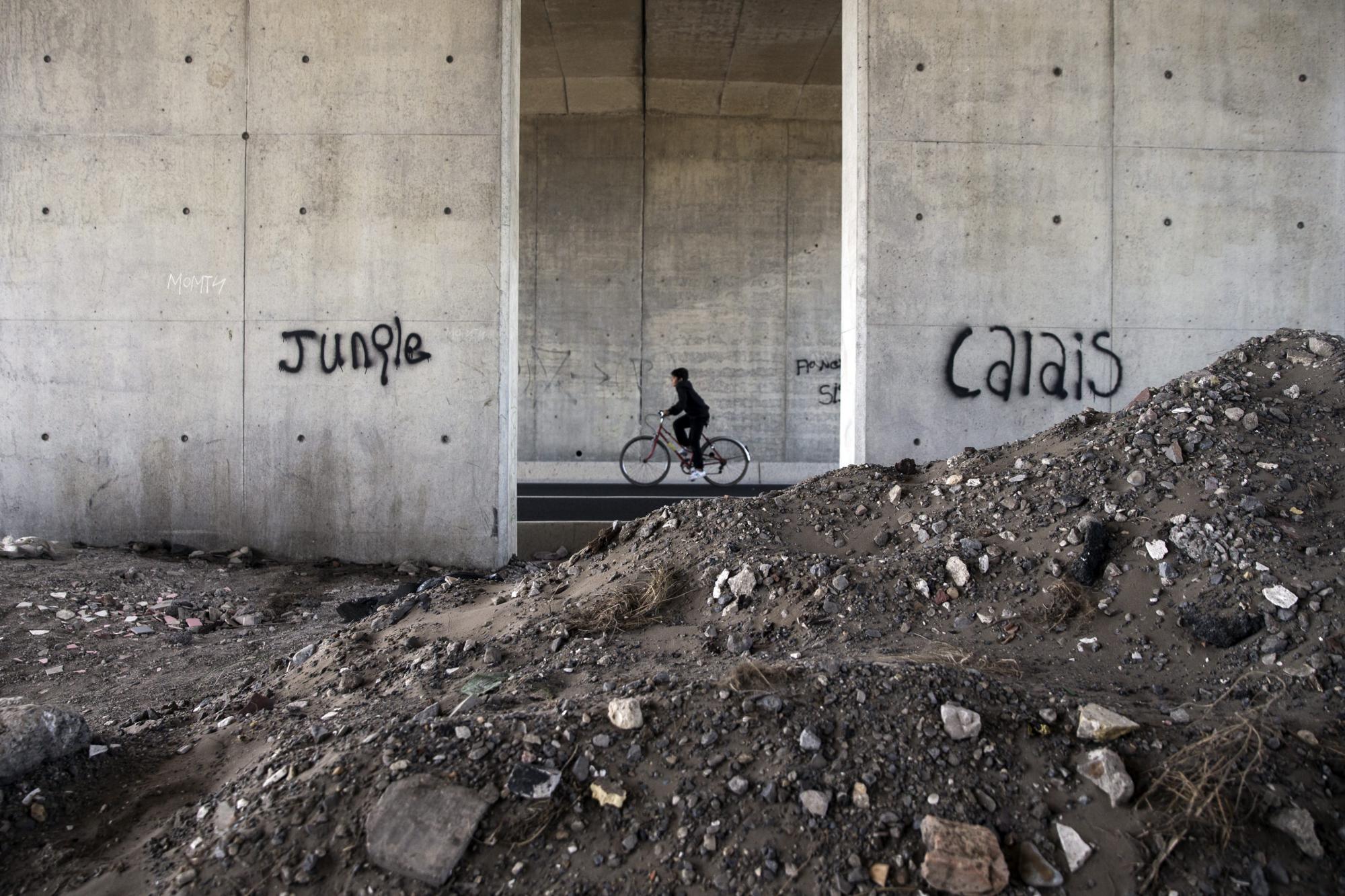Un inmigrante pedalea junto al campamento conocido como La Jungla en las afueras de Calais.
