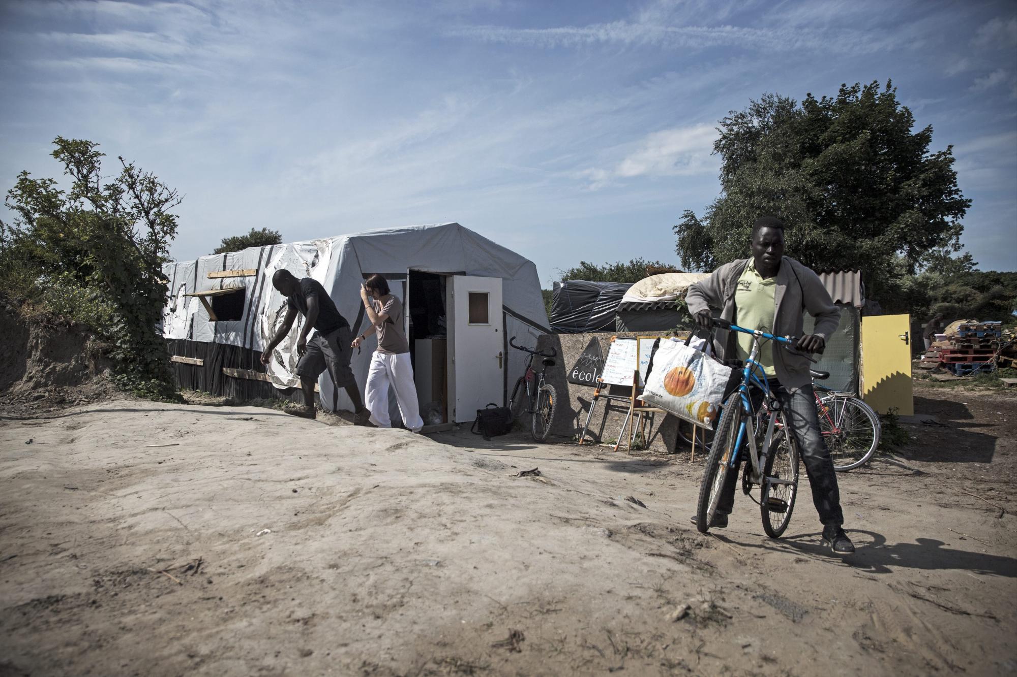 Varios inmigrantes salen de la escuela construida por varios voluntarios y asociaciones francesas en el campamento conocido como La Jungla en las afueras de Calais.