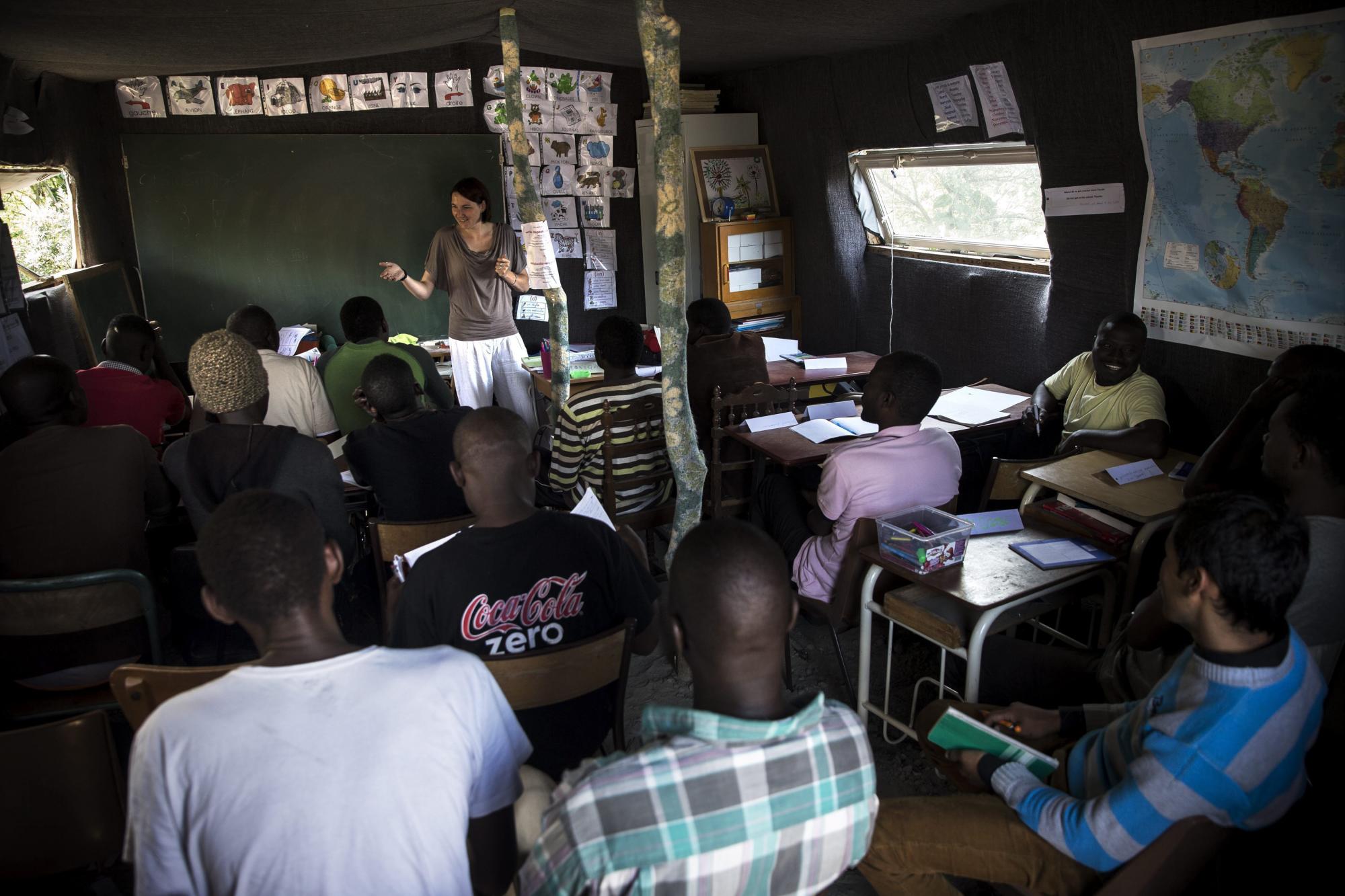 Varios inmigrantes asisten a una clase de francés dada por una voluntaria en el campamento conocido como La Jungla en las afueras de Calais.