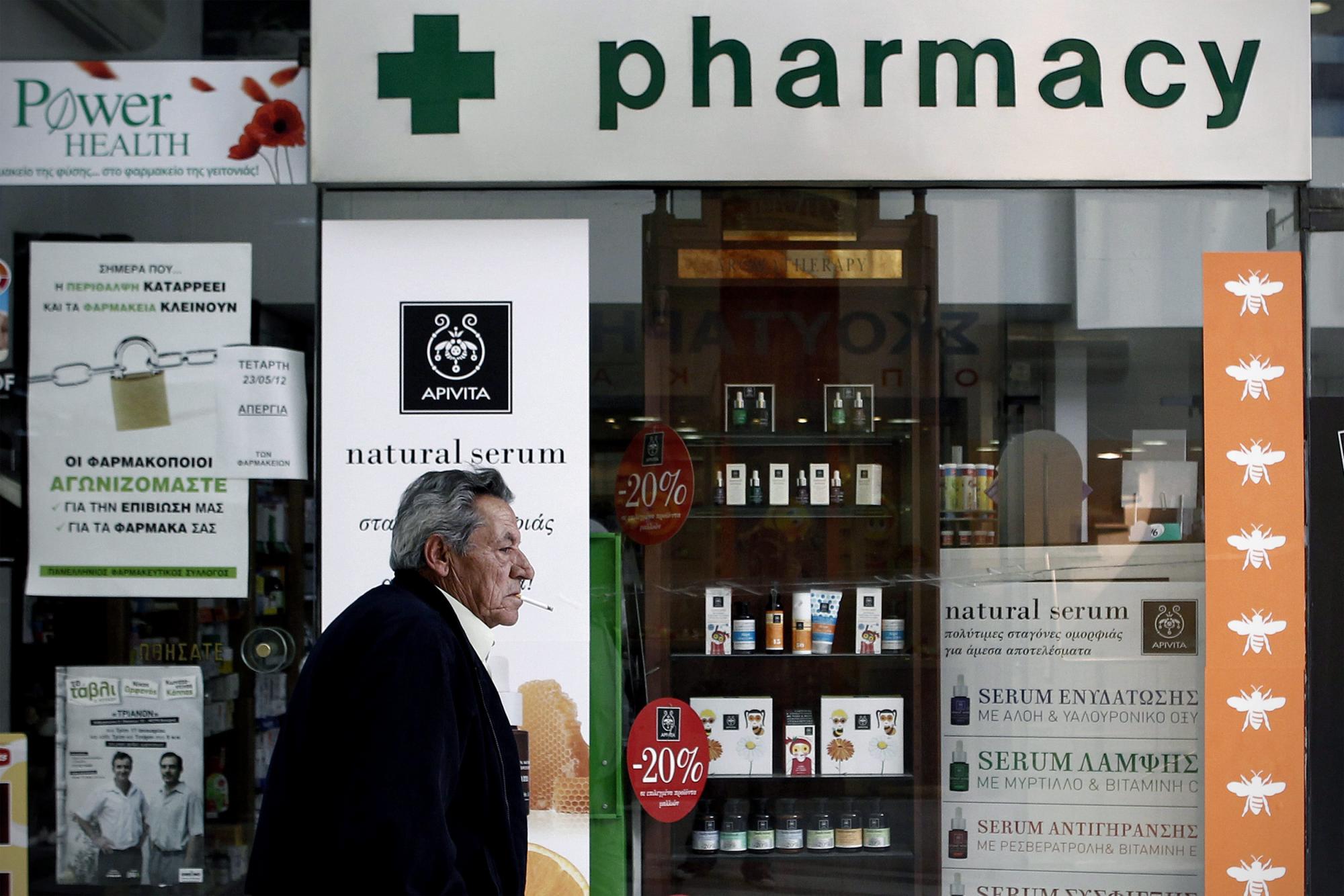 Un hombre camina junto a una farmacia que permanece cerrada durante una jornada de huelga de farmacéuticos en Atenas, Grecia, el 23 de mayo de 2012. Los farmacéuticos protestan por del impago de la deuda del Instituto de Asistencia Social.