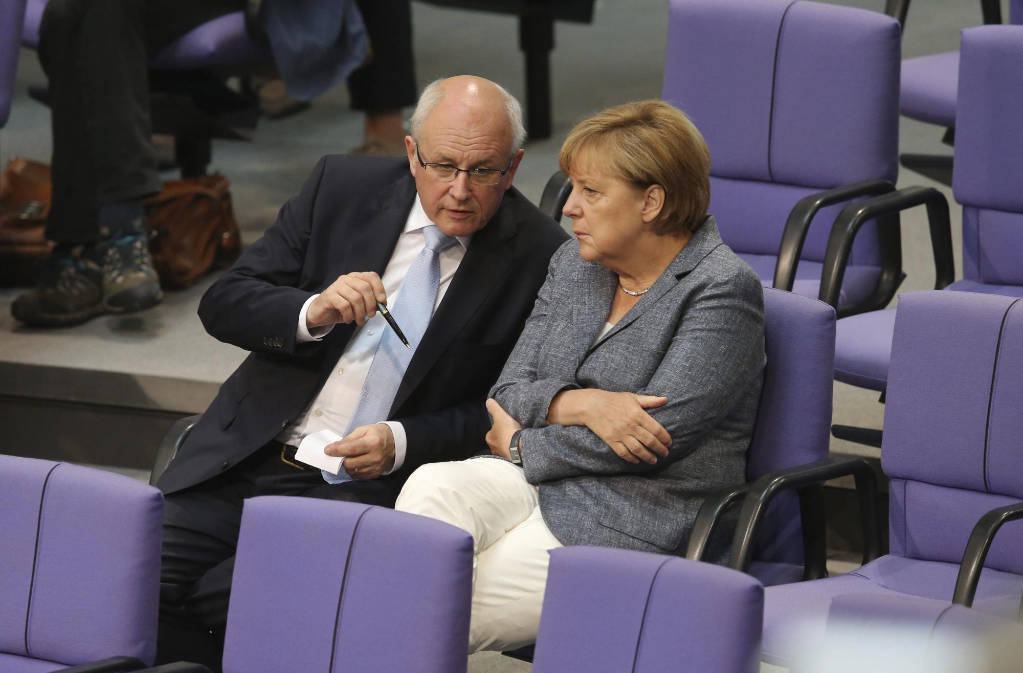 La canciller alemana, Angela Merkel, conversa con el jefe del grupo de la CDU/CSU, Volker Kauder, durante el debate y votación del tercer rescate a Grecia en el Bundestag.