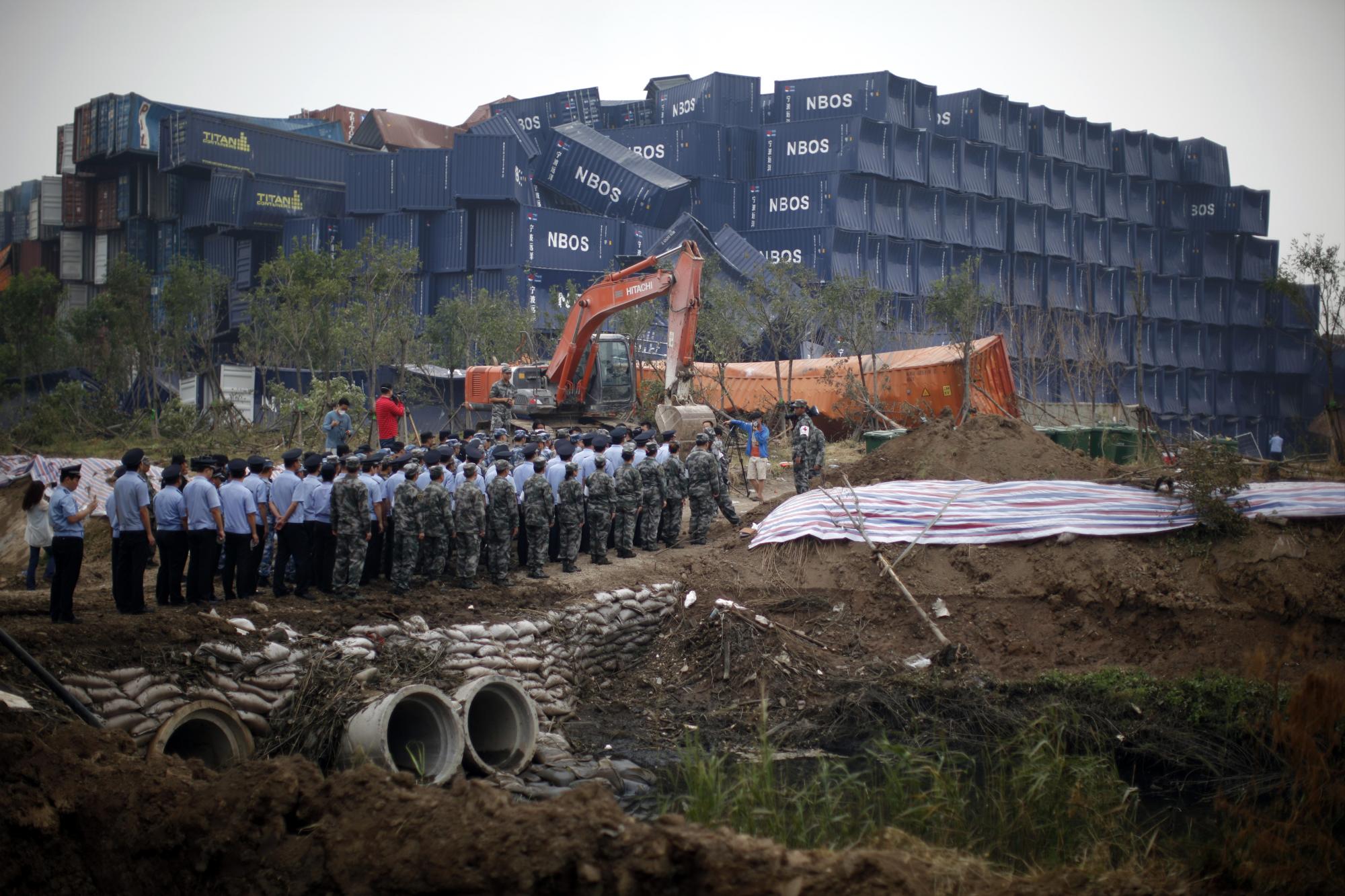 Soldados, policías y paramilitares chinos durante una ceremonia por las víctimas de las explosiones del almacén de Tianjin celebrada cerca del epicentro del desastre, en la municipalidad china de Tianjin, el 18 de agosto de 2015. 