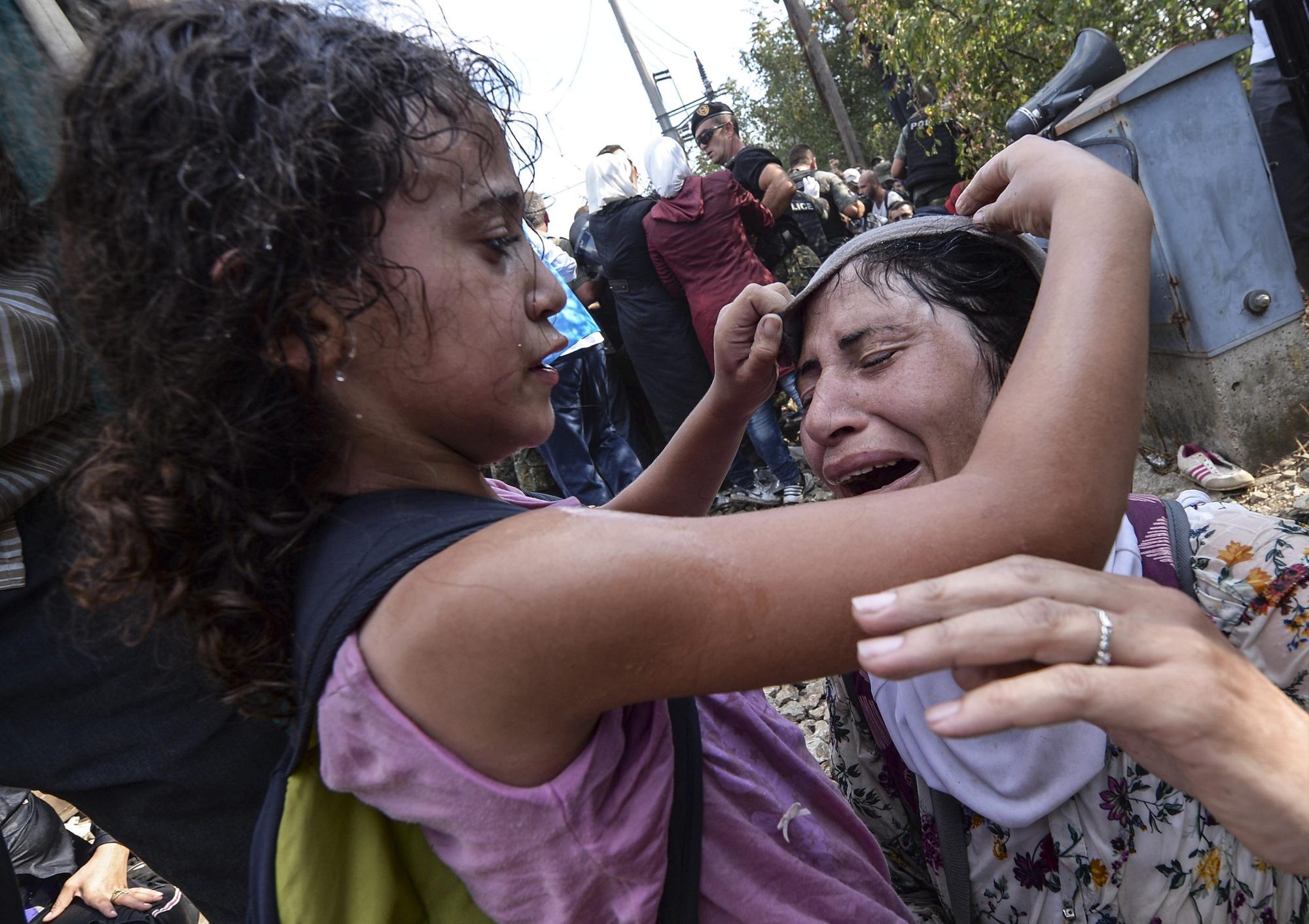 Una niña ayuda a su madre tras cruzar el cordón de fuerzas especiales en la frontera con Grecia en Gevgelija, Macedonia, hoy, 21 de agosto de 2015. 