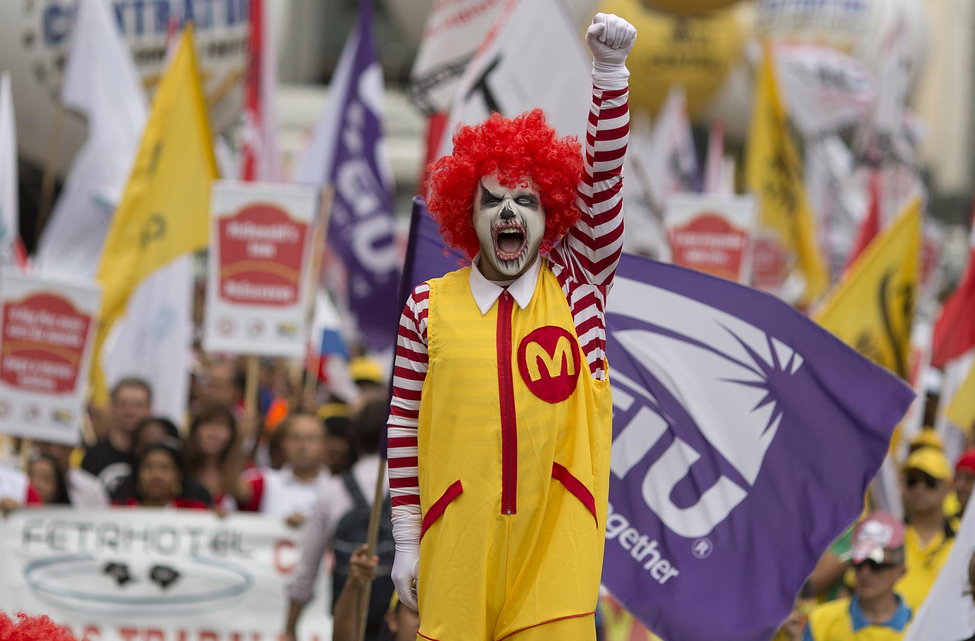 En esta imagen del martes 18 de agosto de 2015, un manifestante vestido como Ronald McDonald protesta para pedir mejores salarios y condiciones de trabajo para empleados de comida rápida en Sao Paulo, Brasil. La protesta reunió a trabajadores de McDonalds, representantes de sindicatos de 20 países y miembros del Sindicato de Trabajadores de Restaurantes.