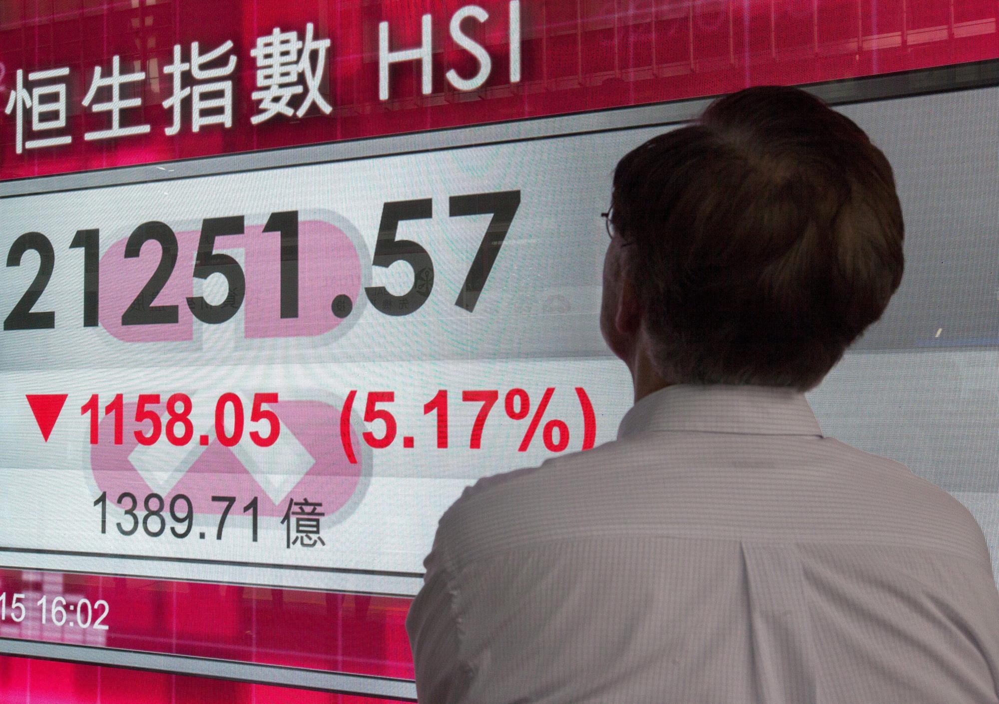 Un viandante observa información bursátil en una calle de Hong Kong (China) hoy, 24 de agosto de 2015. 