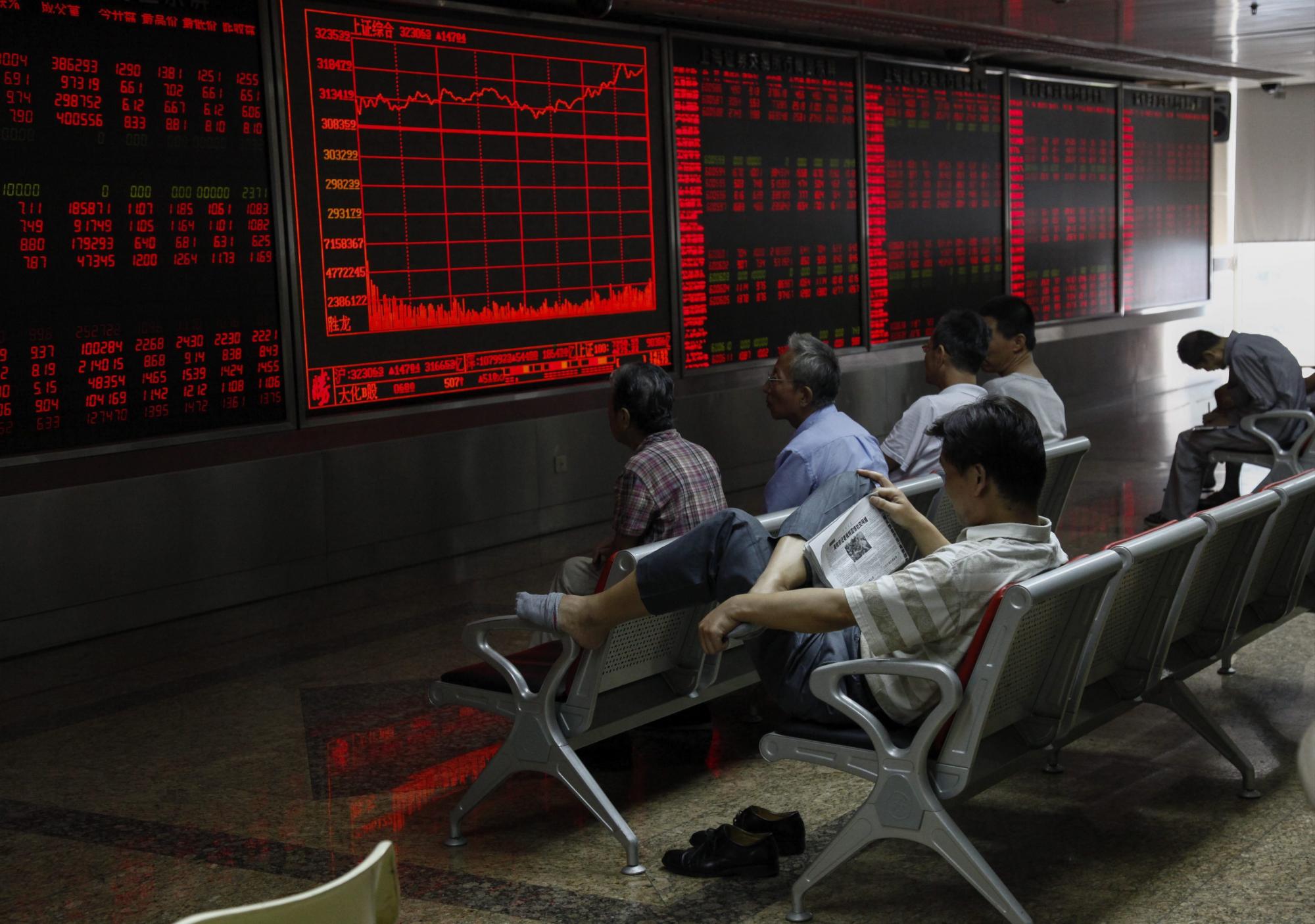 Inversores observan la información bursátil en una pantalla en una oficina de corretaje en Pekín (China).