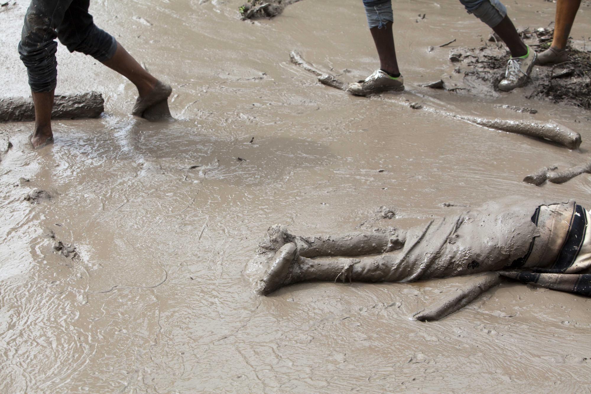 En esta imagen, tomada el 29 de agosto de 2015, el cadáver de una víctima de un deslave yace tendido al aire libre luego de que vecinos recuperaron el cuerpo semienterrado en el lodo por un deslizamiento de tierras provocado por el paso de la tormenta tropical Erika, en Montrouis, Haití. Residentes dejaron al fallecido en la calle con la esperanza de que las autoridades recuperasen el cuerpo más rápido. Erika se disipó a primera hora del sábado pero dejó un rastro de devastación a su paso por la pequeña isla caribeña de Dominica y por partes de Haití, dijeron autoridades. 