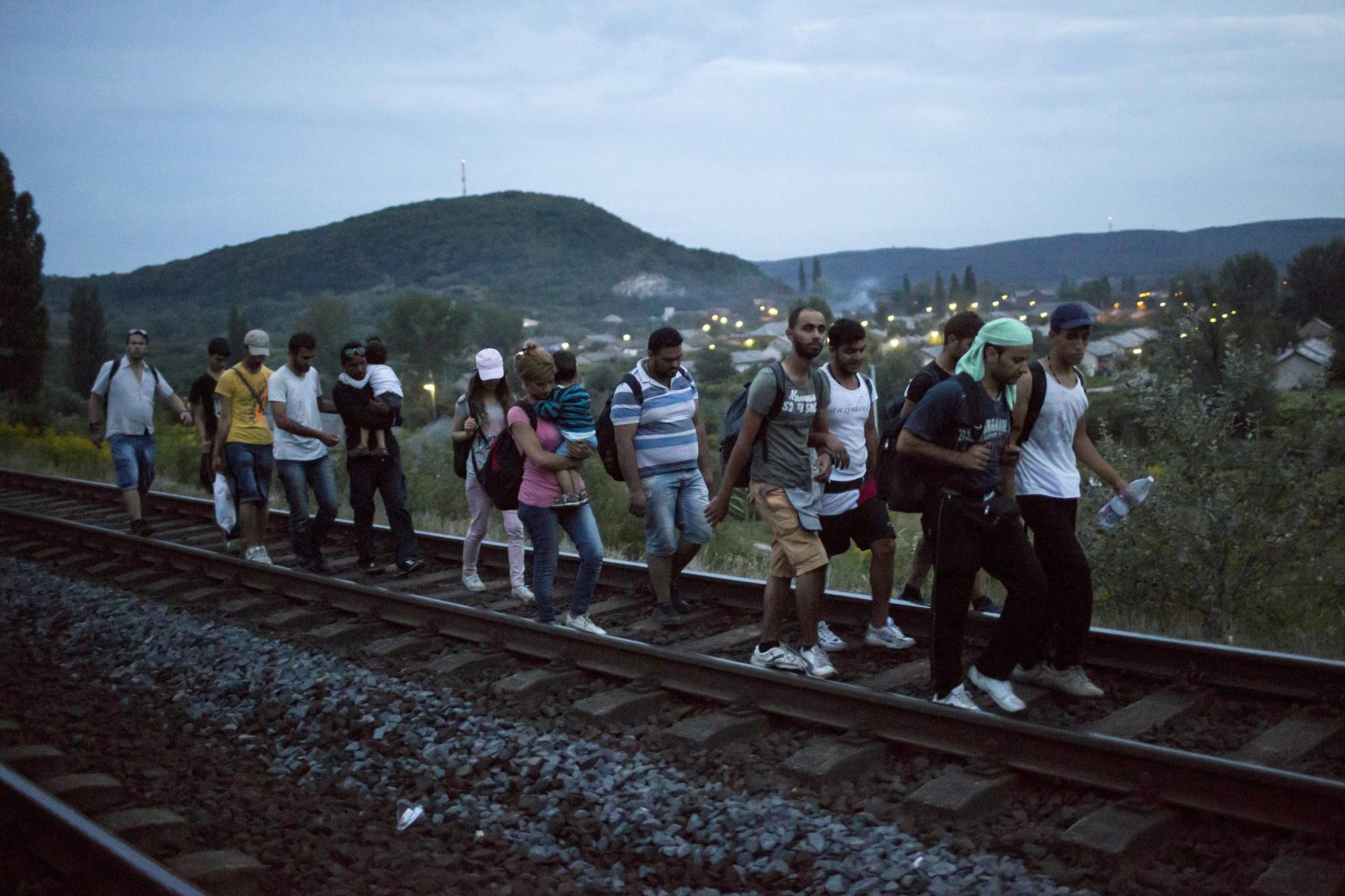 Cientos de migrantes que salieron de la estación de tren de Bicske caminan sobre sobre las vías del tren cerca de Tatabanya.
