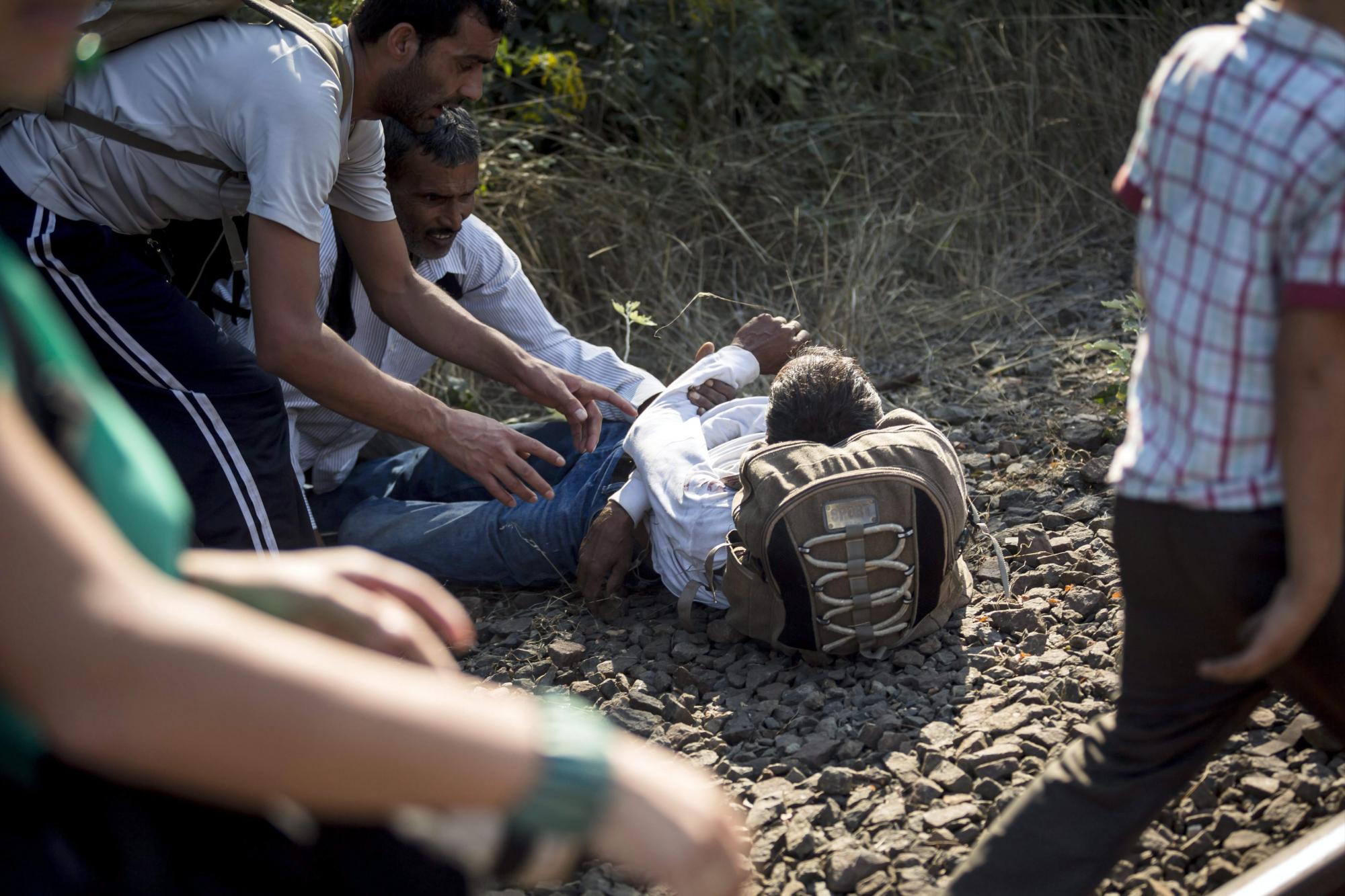 Algunos migrantes prestan ayuda a uno de sus compañeros de camino. De acuerdo con reportes, el hombre murió horas después.