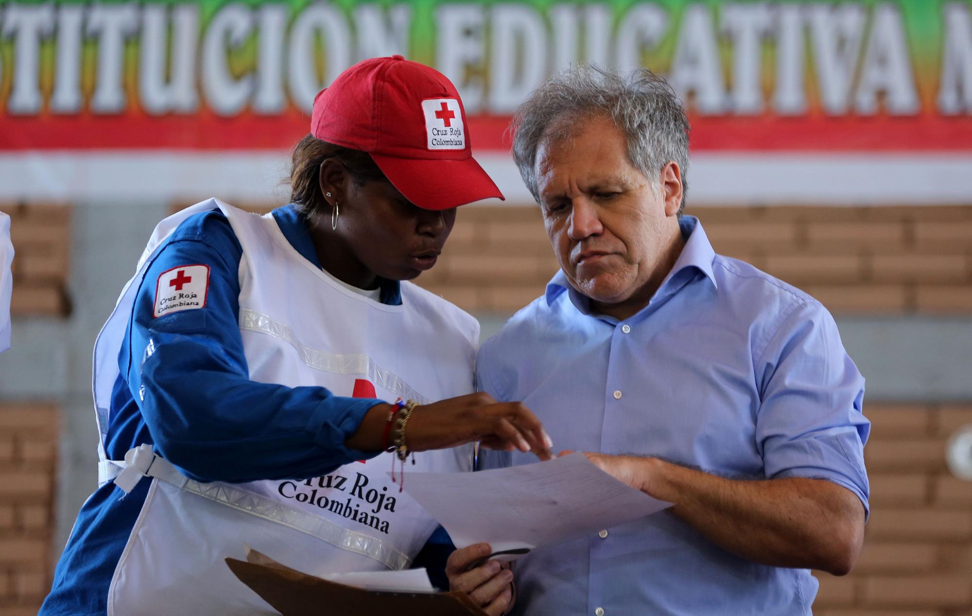 El secretario general de la Organización de Estados Americanos (OEA), Luis Almagro (d), habla con una mujer de la Cruz Roja Colombiana antes de escuchar los reclamos de las personas deportadas que lo esperaban en el coliseo municipal  en el sector de La Parada, cerca a Cúcuta, Colombia, frontera con Venezuela. 