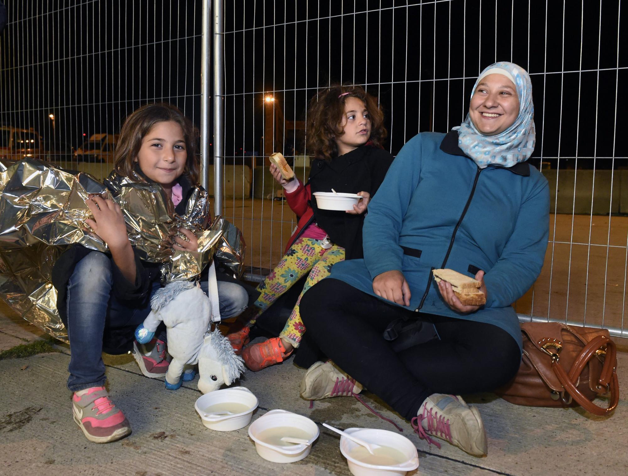Una mujer sonríe junto a dos niñas luego de cruzar la frontera desde Hungría. 