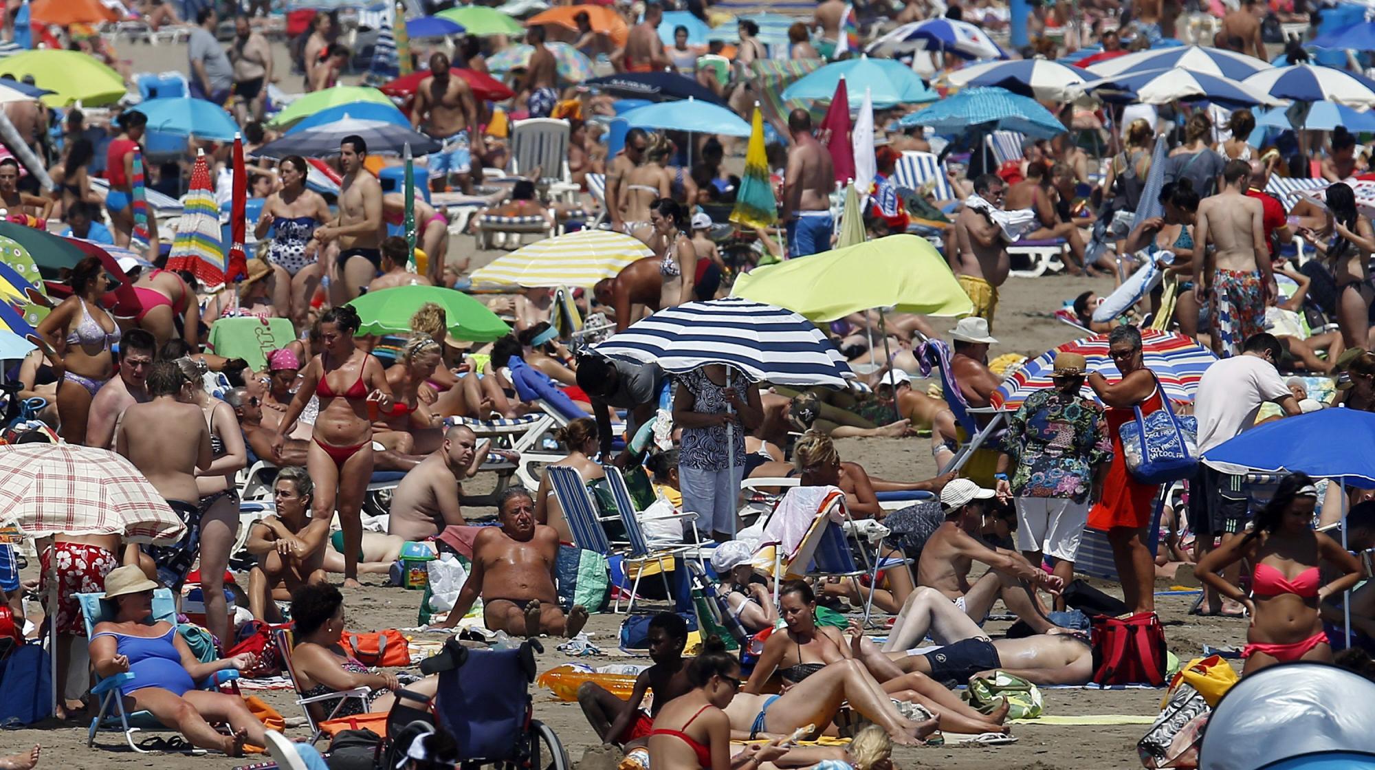 Vista general de la playa de la Malvarrosa adonde ha acudido un gran número de personas para disfrutar del buen tiempo en el ecuador del mes de agosto. 