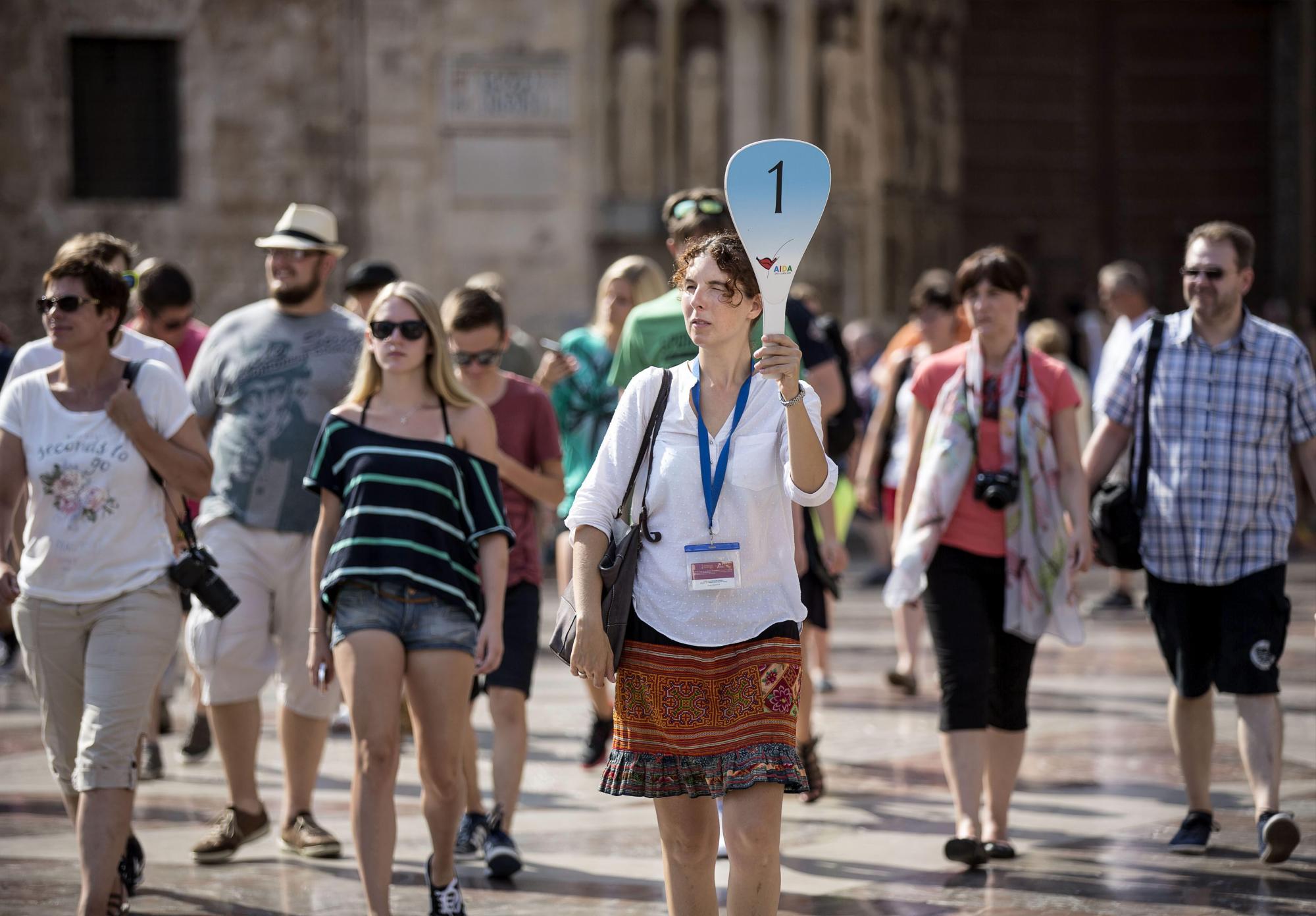 Un grupo de turistas sigue a su guía por el centro histórico de Valencia.  