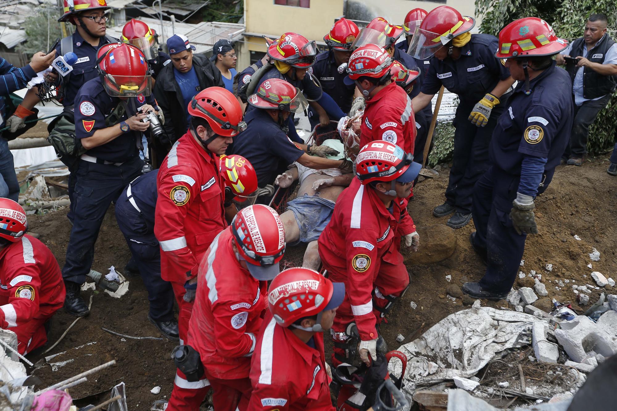 Equipos de rescate rodean el cuerpo de una de las víctimas recuperado de un deslizamiento de tierra en Santa Catarina Pinula, en las afueras de la ciudad de Guatemala, el viernes 2 de octubre de 2015. Por lo menos siete personas murieron y 25 resultaron heridas en la tragedia 